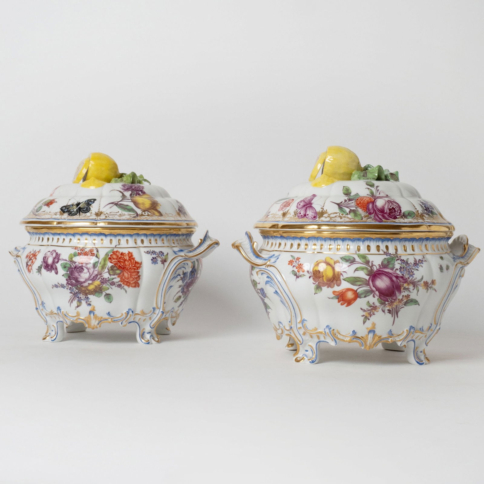 Pair of Nymphenburg Porcelain Covered Small Tureens: After 1975. Each topped with lemon finial and decorated with flowers. Height 9 inches, width over handles 10 inches, diameter 10 inches. With one handle broken off but present; top of one turee