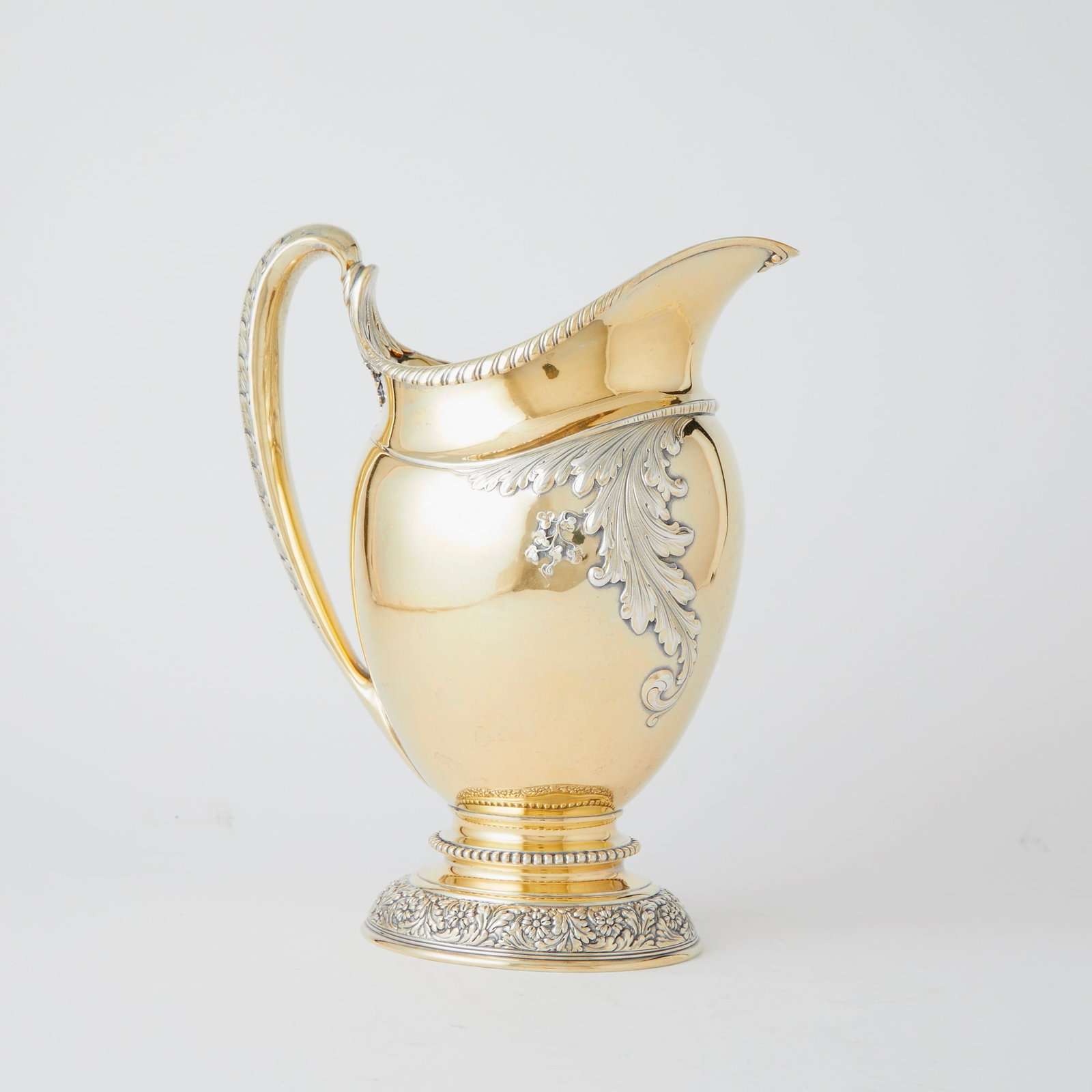 Tiffany & Co. Sterling Silver Gilt Water Pitcher: 1902-1907 The ovoid body chased with foliate scrolls, the oval foot with band of chased flowers and foliate scrolls. Height 10 3/4 inches, approximately 42 ounces. Good condition overal
