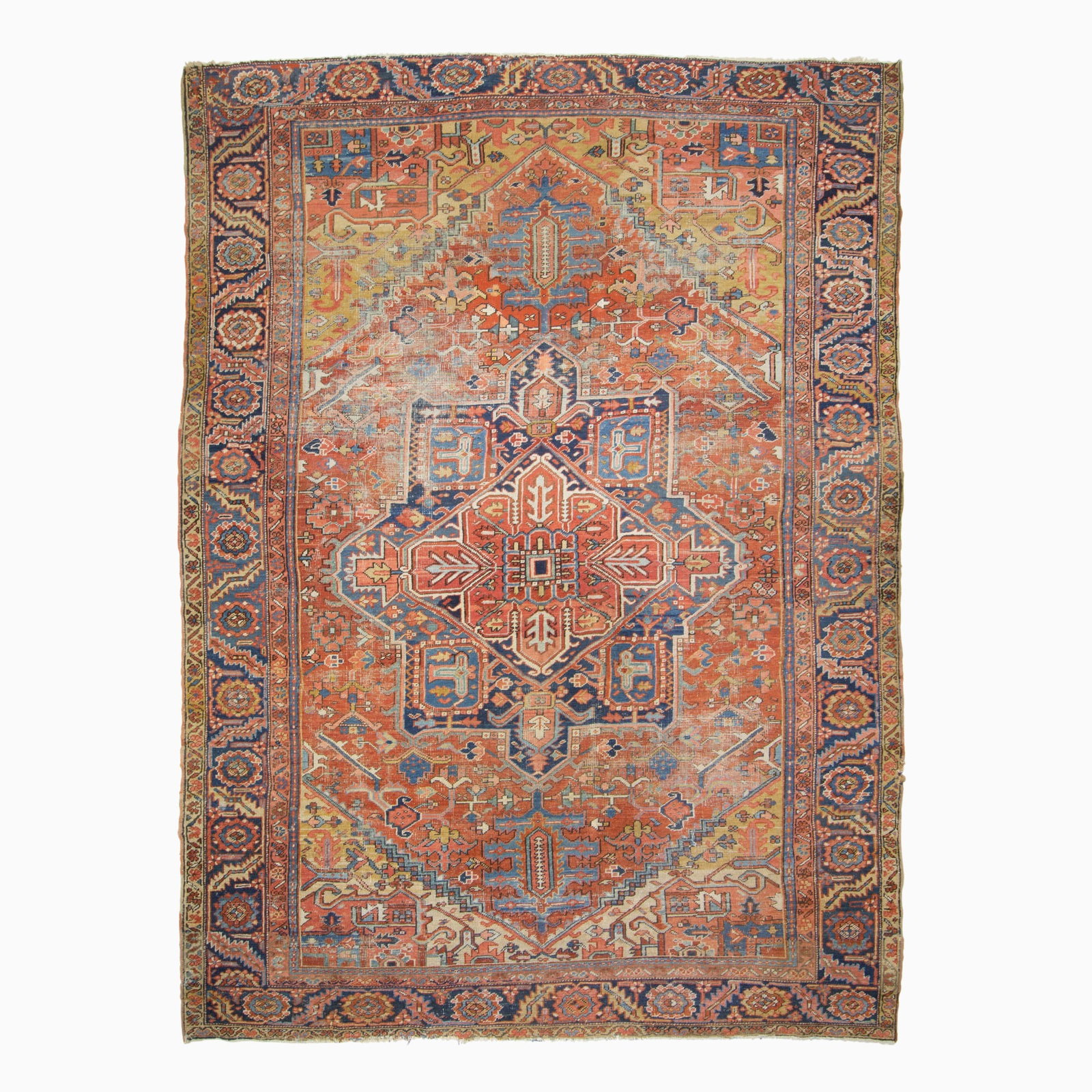 Heriz Carpet: Northwest Persia, circa 1935 The central geometric pendant medallion on the madder field flanked by saffron spandrels is within an indigo rosette and serrated leaf border. (12' 7" x 9' 6")