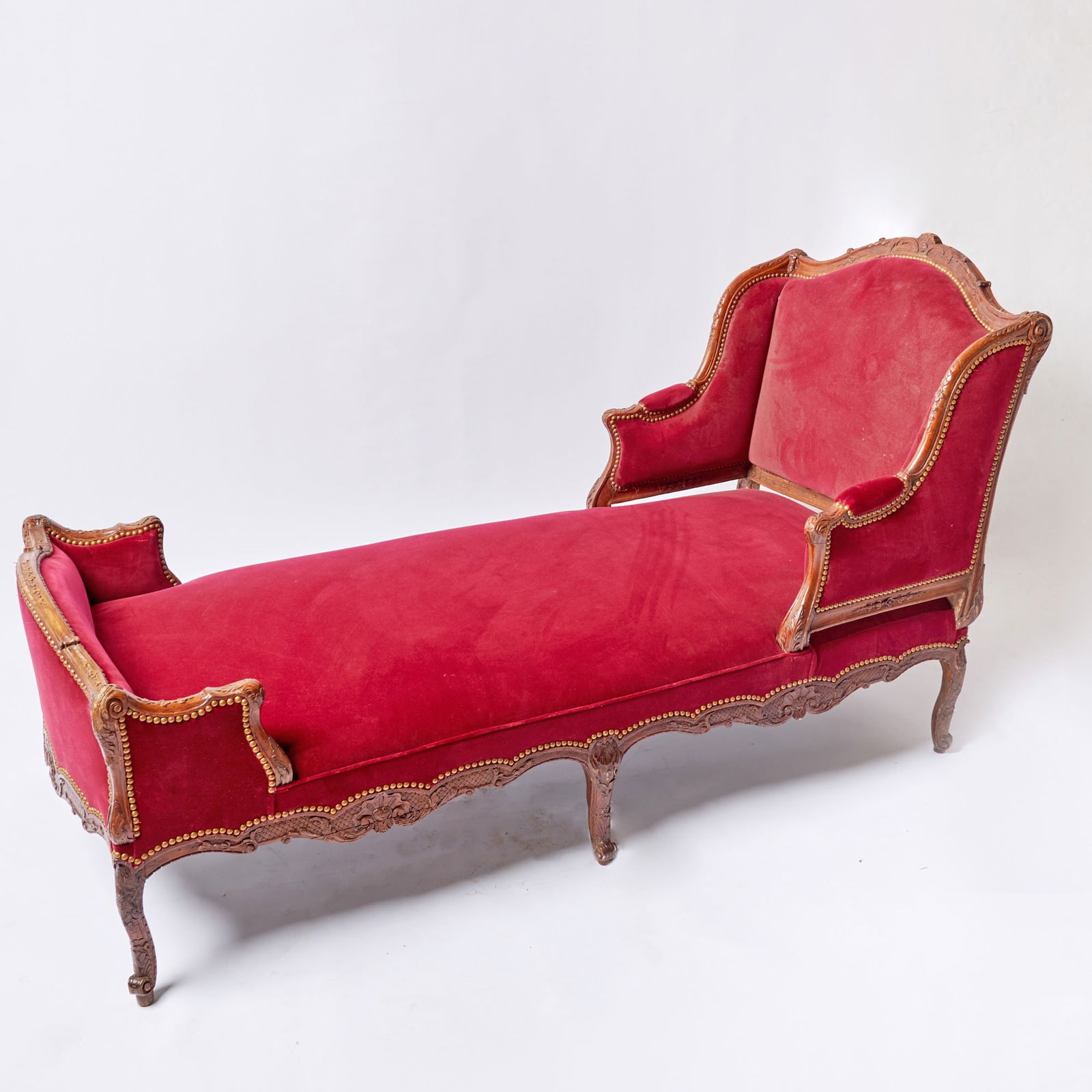 Louis XV Carved Walnut Chaise Lounge: Mid-18th century The shaped toprail centered by a carved shell and acanthus scrolls above foliate-carved downswept arms and a squab cushion, the apron ornately carved with rocaille, latticework, scrol