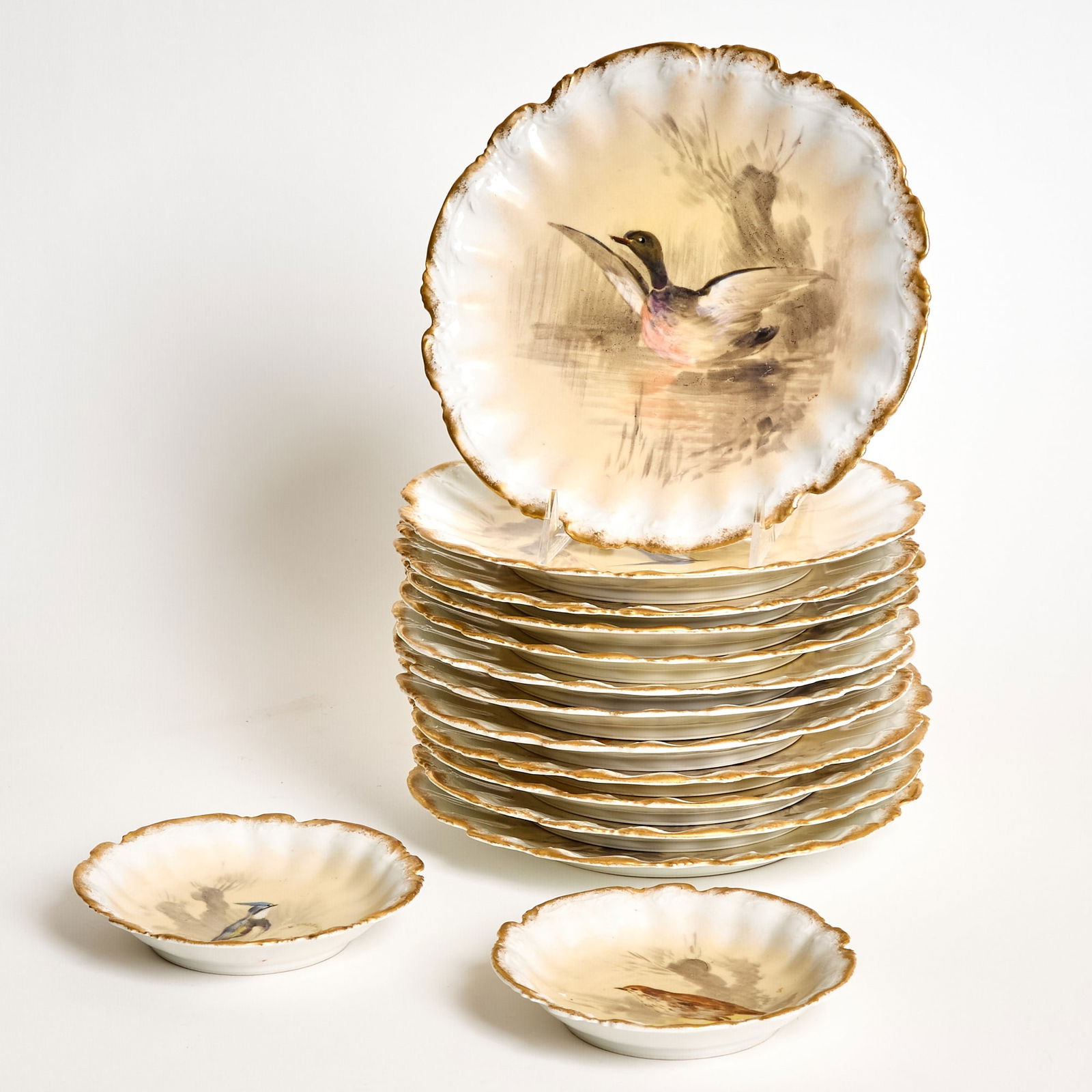 Limoges Hand-Painted Bird Porcelain Partial Service: Comprising twelve plates, diameter 9 1/4 inches; and two saucers, diameter 6 inches.