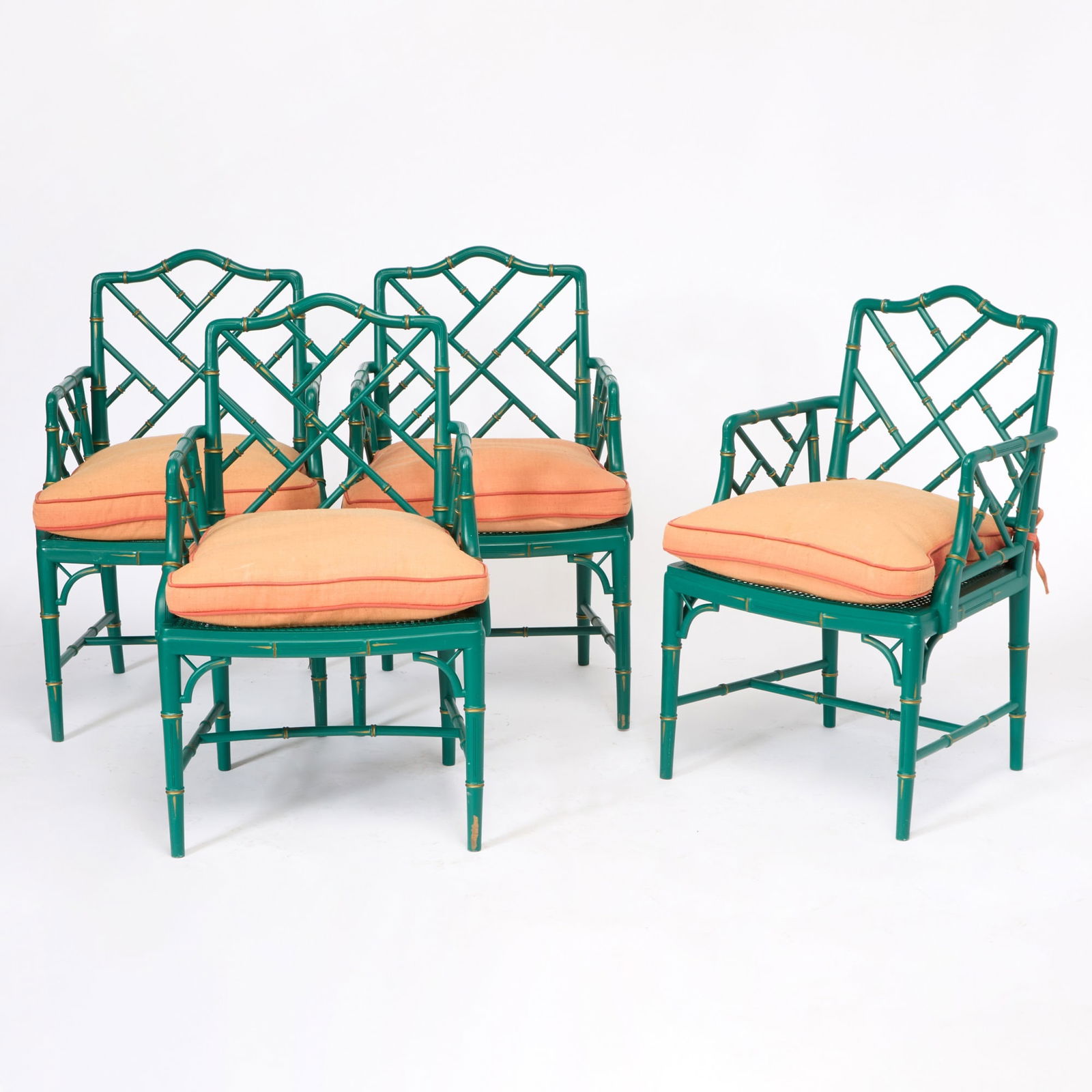 Set of Four Phyllis Morris Green Painted Faux Bamboo Armchairs: Each with a coral linen upholstered squab cushion. Height 36 1/2 inches, width 22 1/4 inches, depth 18 1/2 inches, seat height 16 inches. One cane seat broken, some rubbing and losses t