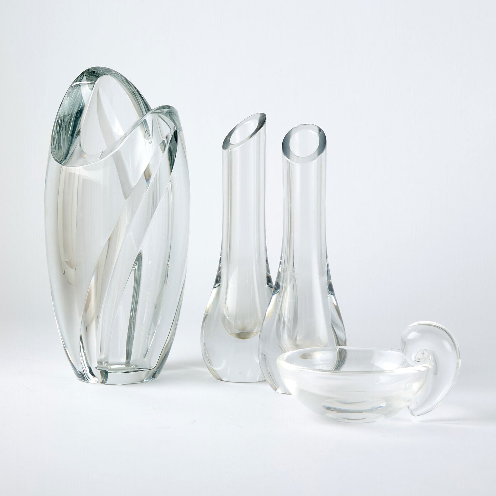 Group of Three Baccarat Blown Glass Vases: Late 19th/early 21st century Each in colorless glass, height of tallest 11 1/2 inches; Together with a Steuben Blown Glass Olive Dish. Of round form with a scroll handle, in colorless glass, signed St