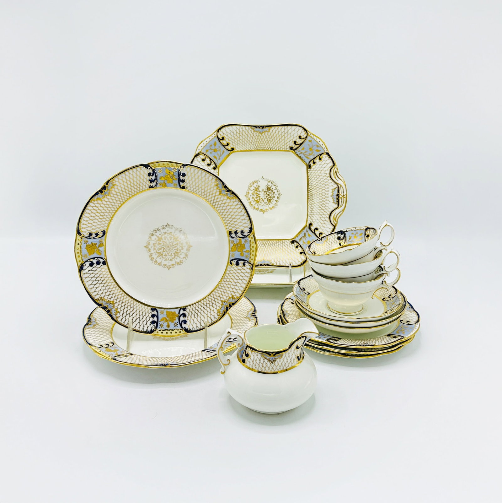 Hammersley & Co. Gilt and Cobalt Decorated Part Luncheon Service: Comprising: Eleven luncheon plates, diameter 8 3/4 inches. Twelve salad plates, diameter 7 inches. Eleven saucers Seven teacups Cream jug Two serving dishes, length over handles 10 1/2 inch