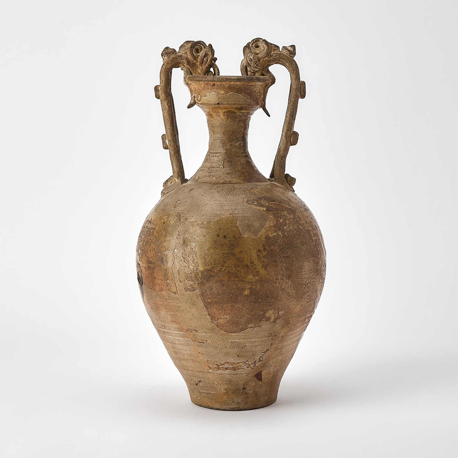 A Chinese Glazed Pottery Amphora Tang Dynasty: Of typical form with tapering ovoid body and two arched dragon-form handles issuing from shoulder and joining cupped rim. (Height 15 1/4 inches) Purchased in London, 1950s