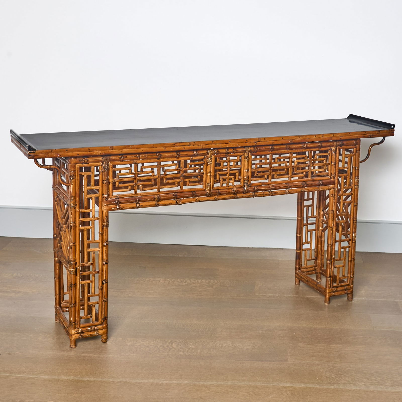 Brighton Pavillion Style Bamboo Console Table: The black-lacquered rectangular top above a geometric fretwork frieze, raised on corresponding legs. Height 32 3/4 inches, width 65 inches. Minor surface wear to top and ends. Overall condition good.