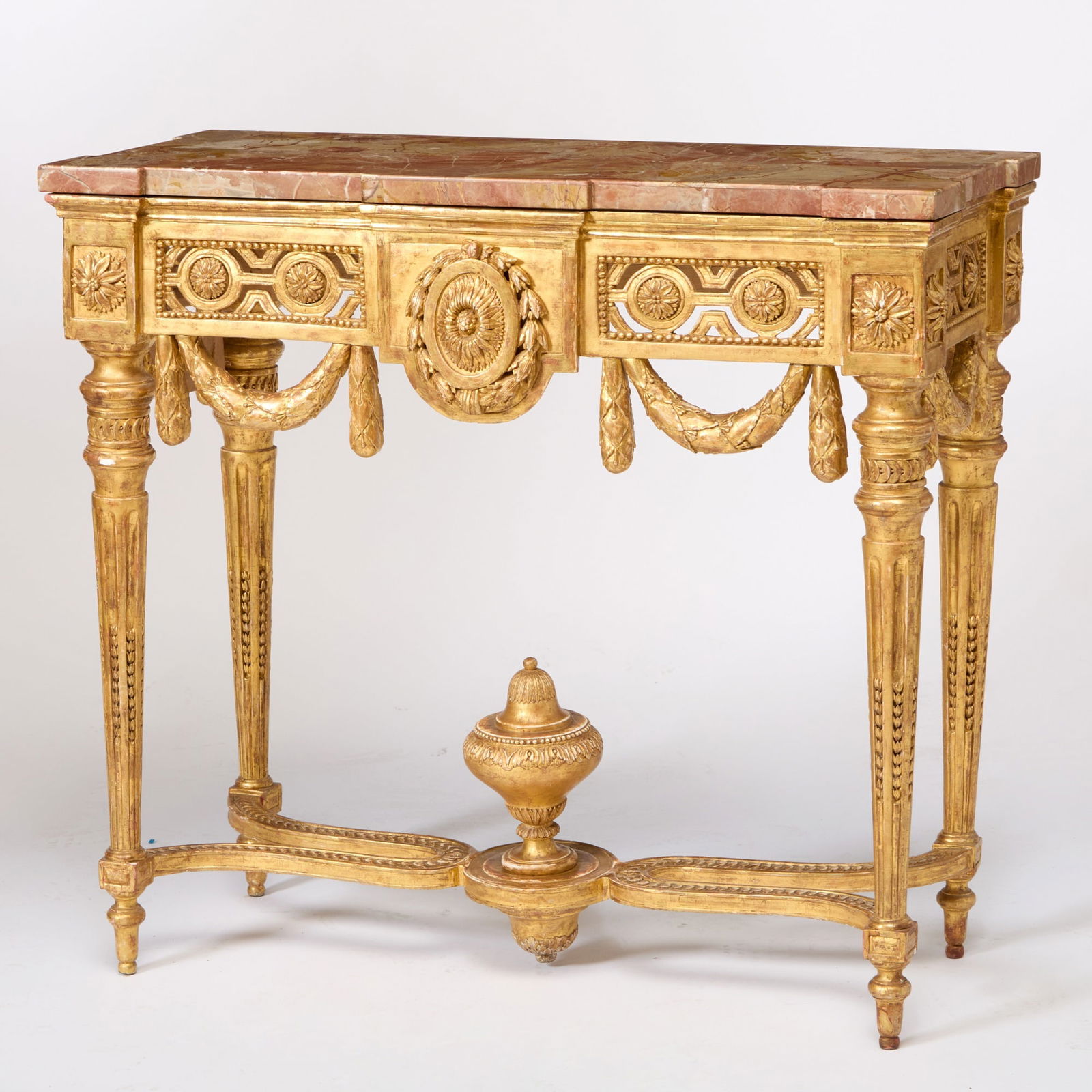 Swedish Gustav III Giltwood Console: Last quarter 18th century The later shaped rectangular pink, white and yellow veined marble veneered top above a carved frieze centered by an oval sunflower medallion with husk and berry border flanke