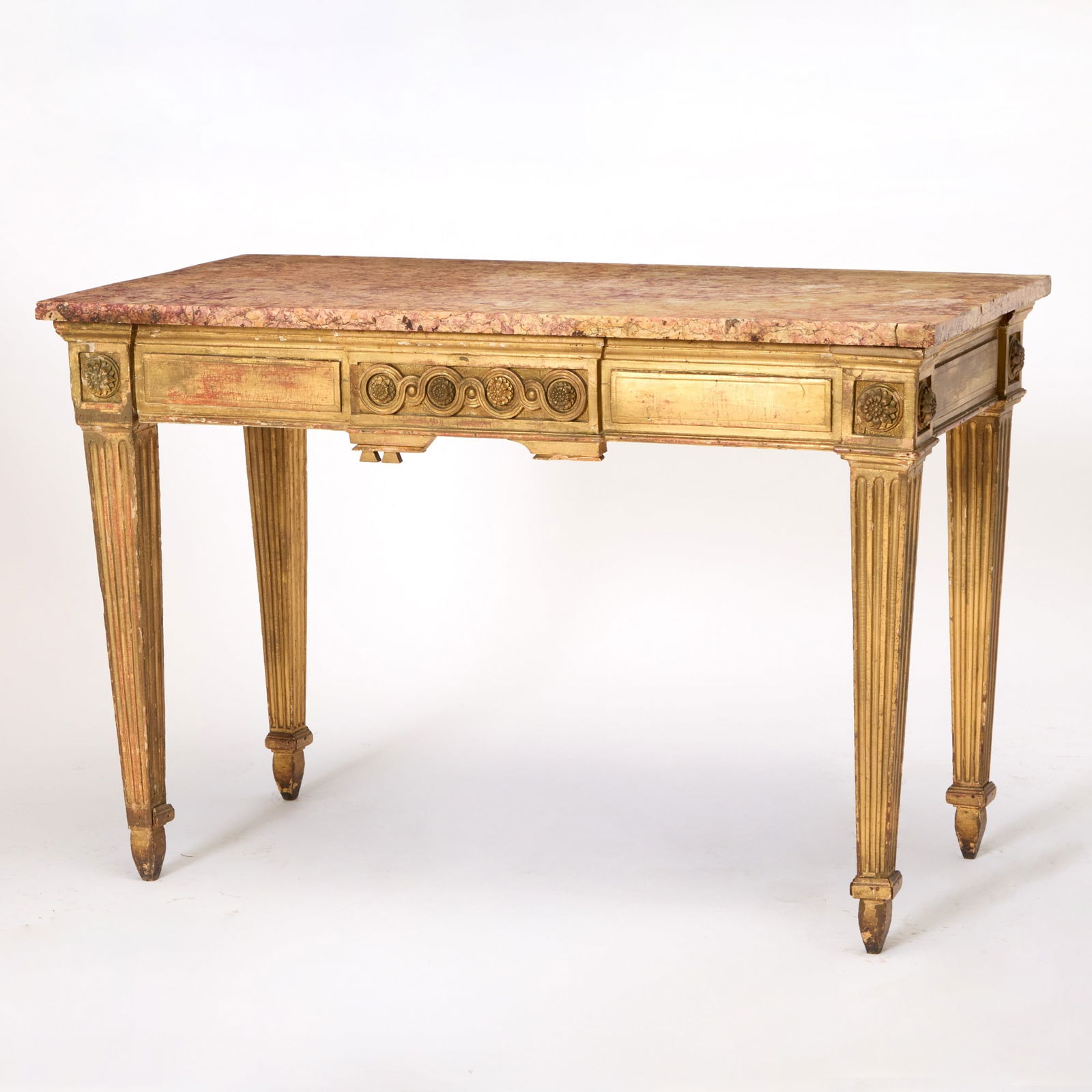 South French Provencal Louis XVI Giltwood Console: Late 18th century The pink and red veined marble top above a molded and carved frieze centered by a guilloche-carved central panel flanked by rosettes, on tapering fluted legs and shaped feet. Height