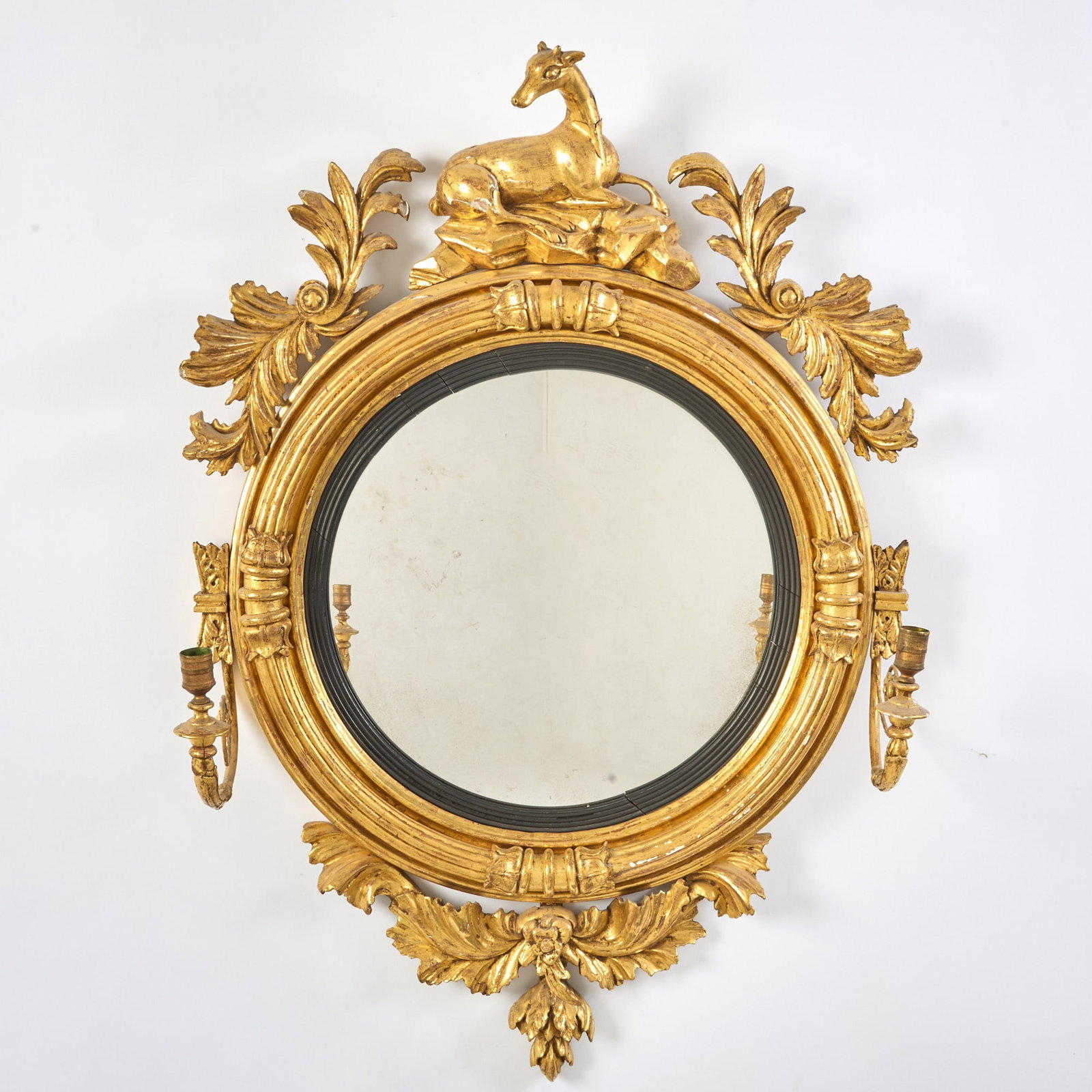 Regency Giltwood Convex Girandole: Circa 1820 The recumbent doe cresting above a reeded and lotus-clasp surround, issuing two scrolling candlearms above a leafy apron. Height 39 1/2 inches (100.3 cm), width 25 1/2 inches (64.7 cm). Wi