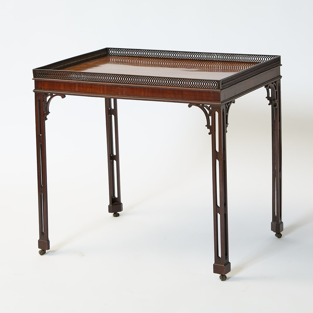 George III Style Mahogany Tea Table: The rectangular top with pierced lozenge gallery above a molded frieze and scroll brackets on pierced legs and casters. Height 28 3/4 inches (73.1 cm), width 30 1/4 inches (78.2 cm), depth 22 1/4 inch