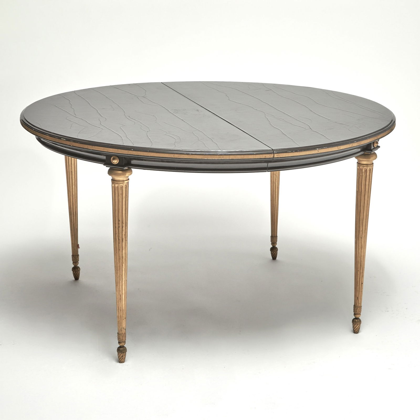 Black Lacquered and Giltwood Extension Dining Table: Style of Maison Jansen Height 29 inches, diameter closed 51 1/2 inches. With one leaf, width 25 1/2 inches.