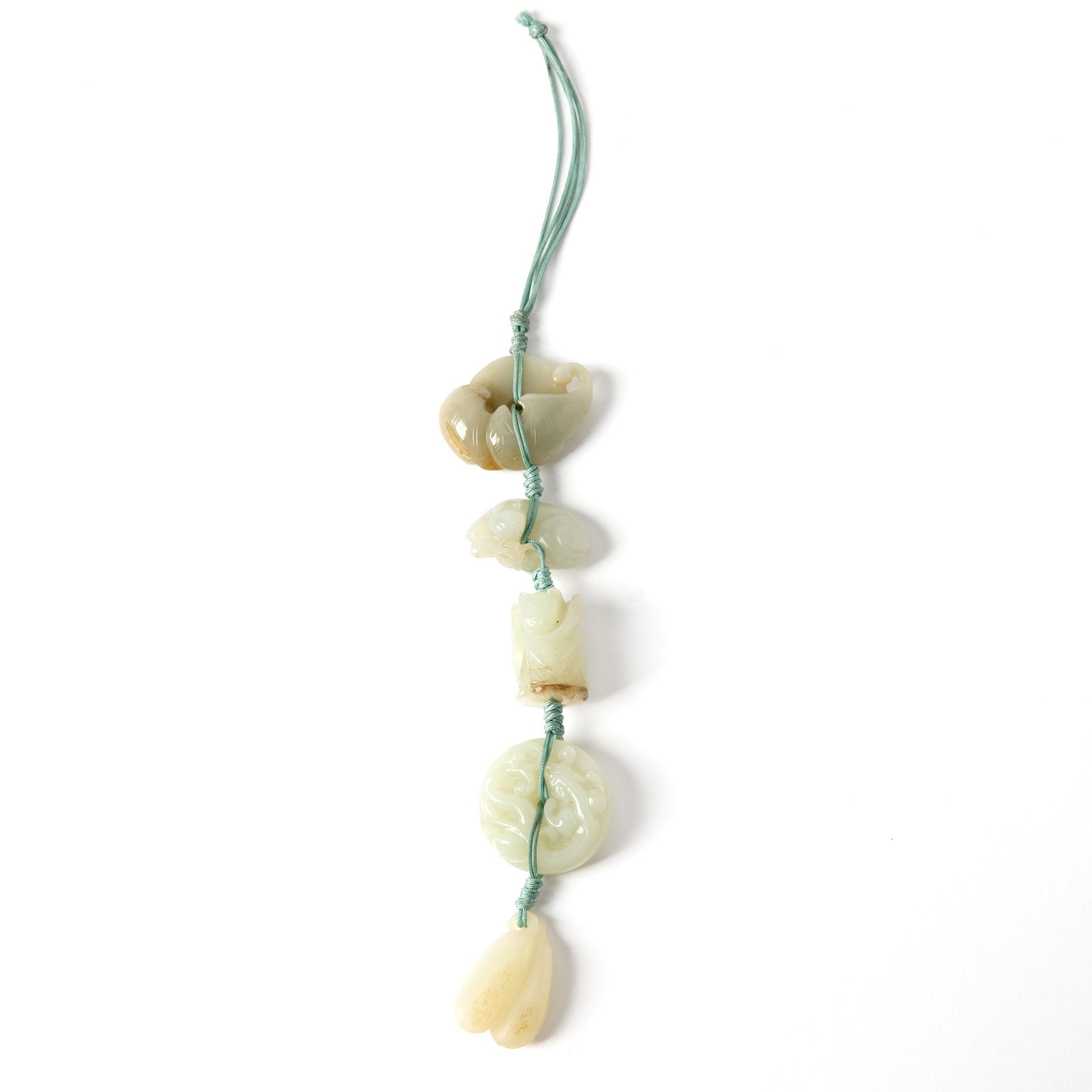 A Chinese Carved Jade Pendant Qing Dynasty: Comprising a bat perched on a coin, a cat with a butterfly, a figure holding a lotus stem, a chilong on a bi disc, and an aubergine-shaped grouping. (Length 7 inches)