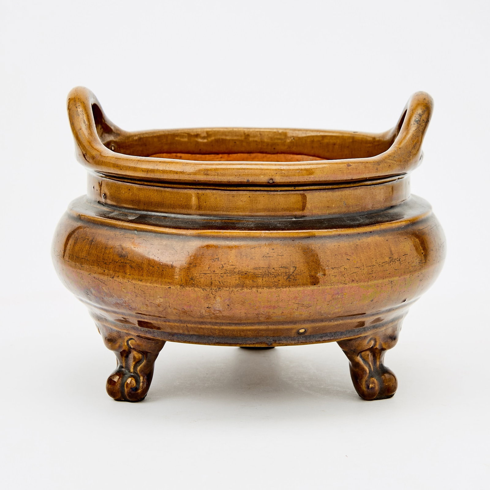 A Chinese Brown Glazed Censer: The compressed body raised on three cabriole legs, surmounted by a pair of upright loop handles. (Width 8 1/2 inches)