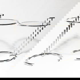 Pair of Chromed Metal and Glass Occasional Tables: After Eileen Gray, later reissues Height 26 inches, diameter 21 inches.Provenance:Mr. and Mrs. Leo and Evelyn D. Farland, New YorkThence by descent to the estate