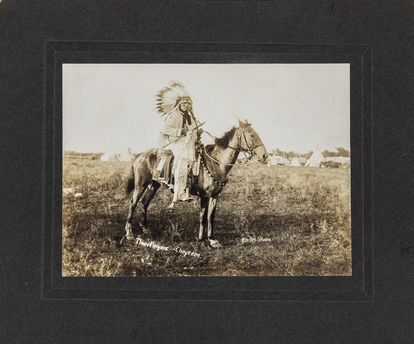 Photograph of the Cheyenne Chief Three Fingers: [NATIVE AMERICANS] [WHITE'S STUDIO]. Photograph of Cheynne Chief Three Fingers on horseback. Gelatin silver print, on the embossed studio card mount, circa 1898. Image 6 x 8 inches (15 x 20) cm on