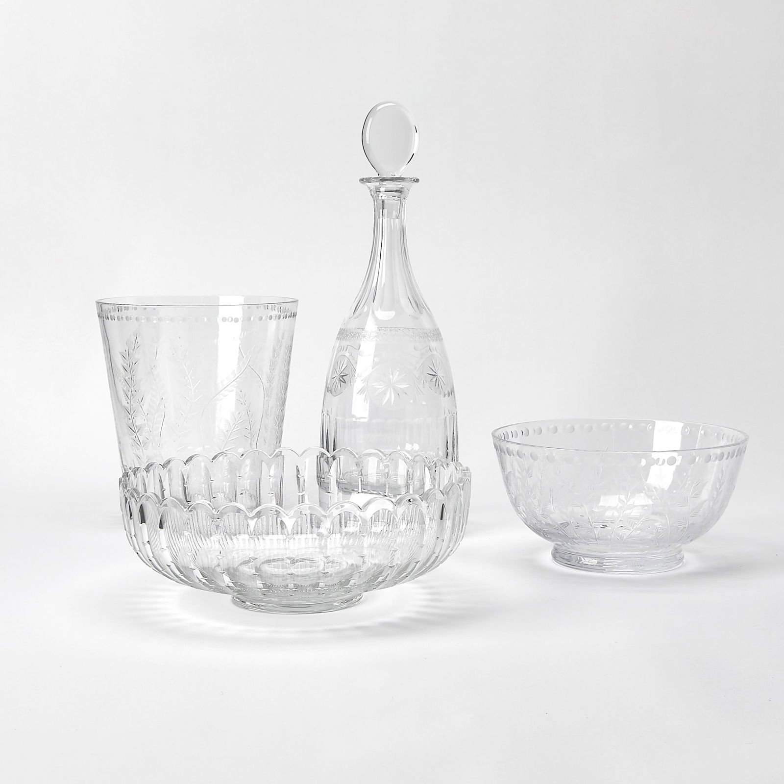 Group of Four William Yeoward Glass Table Articles: Comprising a decanter with stopper; ice bucket; and two bowls. Height of decanter 15 1/4 inches; height of bucket 9 inches; diameter of larger bowl 11 1/2 inches.