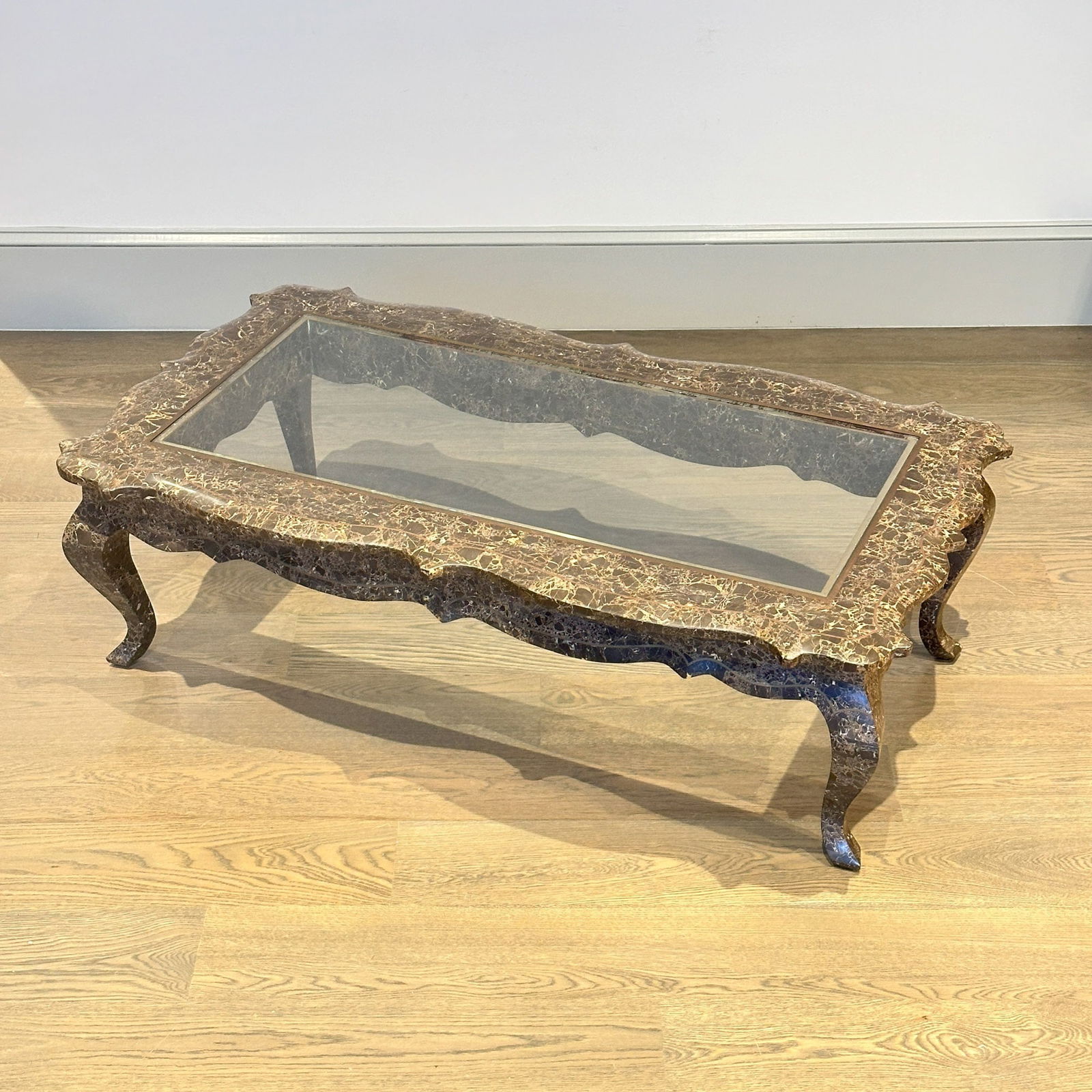 Brass-inlaid Marble Low Table: The inset glass top on a tesselated frame with serpentine sides, rolled apron, and brass stringing raised on cabriole legs.Height 15 1/2 inches, width 52 inches, depth 29 1/2 inches.