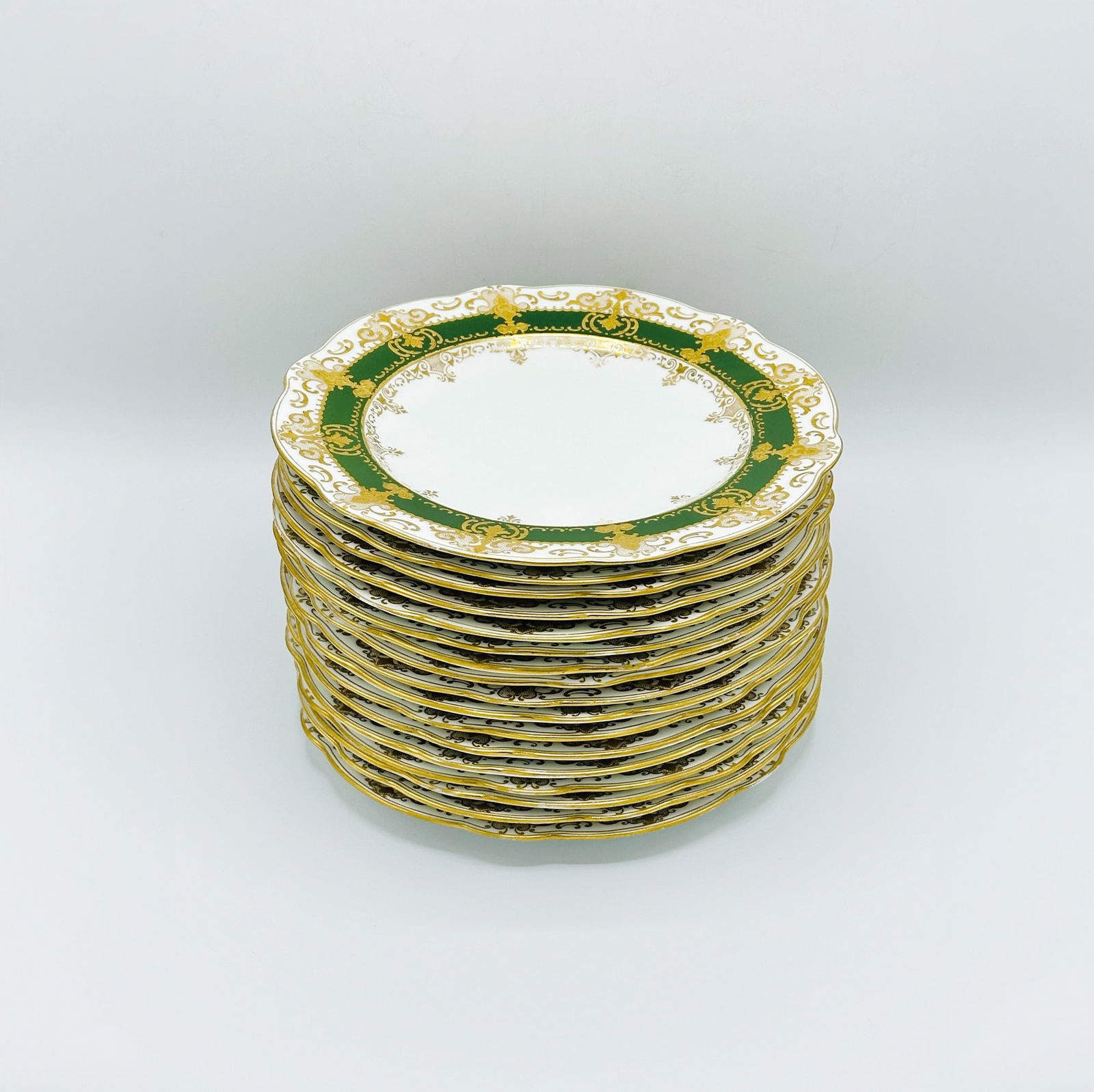 Set of Seventeen Coalport Porcelain Dinner Plates: With green band and raised gilt rococo borders.Diameter 10 1/2 inches.Some with Tiffany & Co., New York, retailer marks. some wear to gilt, one with very tight 3 inch hairline.