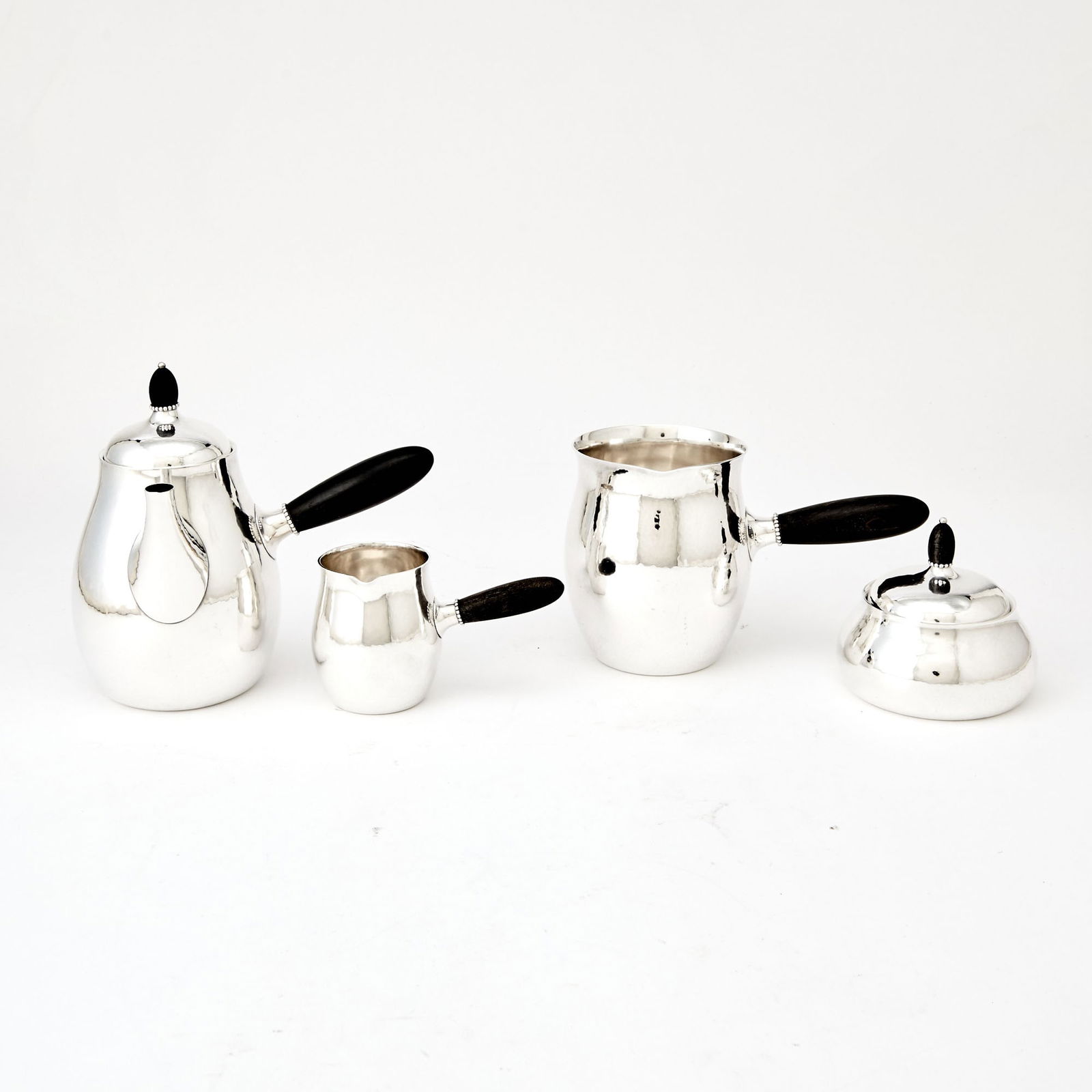 Georg Jensen Sterling Silver Coffee Service with Ebony Handles: Design attributed to Georg Jensen, design no. 80, post-1945 Comprising a coffee pot, no. 80 A, height 6 3/4 inches; hot milk pitcher, no. 80 E, covered sugar bowl, no. 80 C; and a creamer, no. 80 C. T