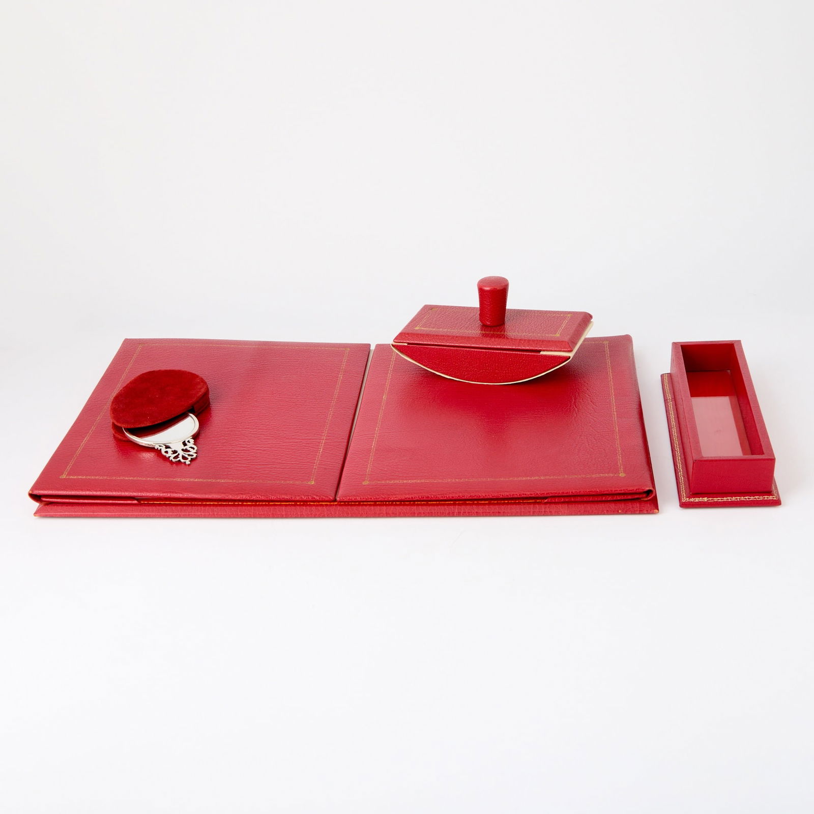 Smythson Gilt-Tooled Red Leather Desk Accessories: Late 20th century Comprising a desk organizer, length 18 1/4 inches; pen tray, length 9 1/4 inches; blotter, length 6 1/4 inches; Together with a Silver Plated Mirror, length 4 inches.