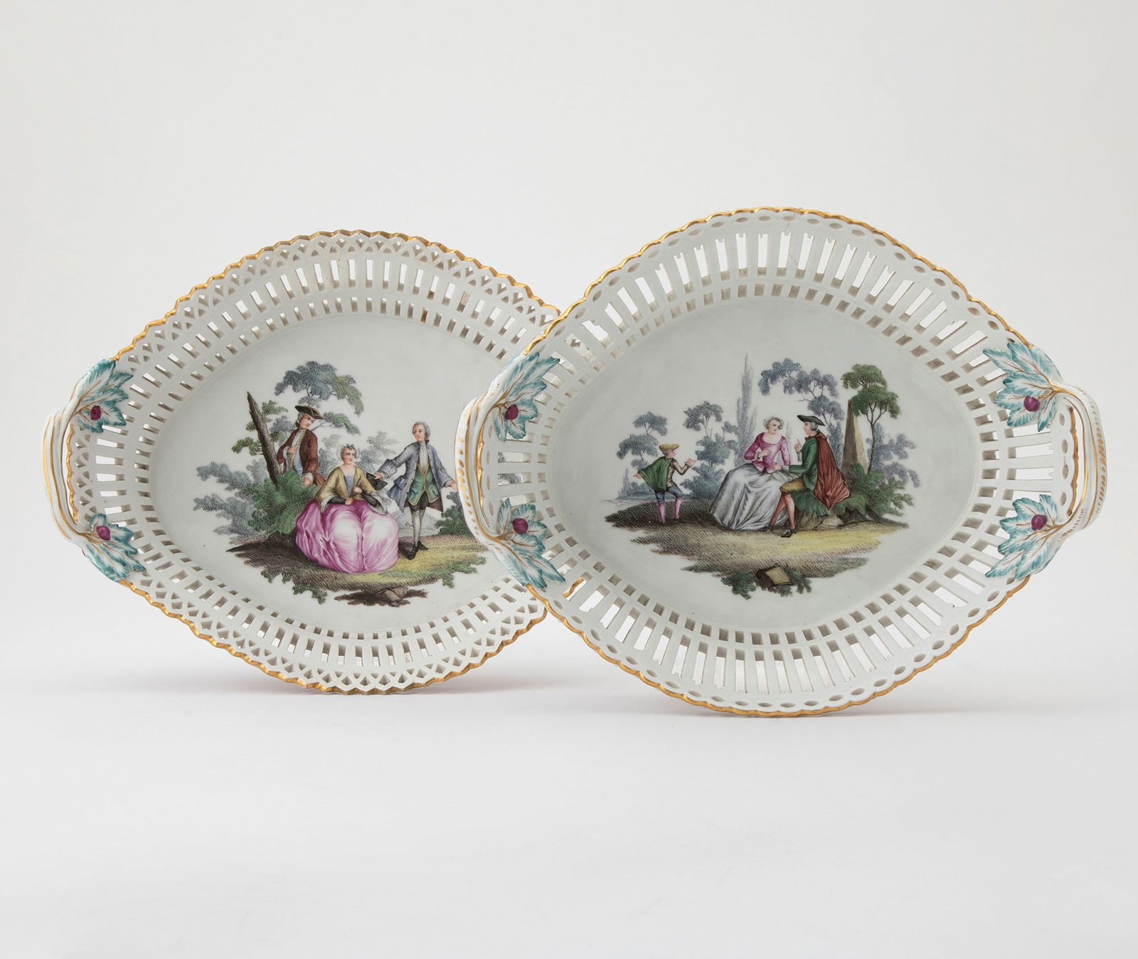Pair of Berlin KPM Porcelain Reticulated Oval Twin-Handled Baskets: Second quarter 19th Century Each center decorated in colors depicting elegant figures in a wooded landscape within an openworked border with molded gilt rim. Each with sceptre mark in underglaze blue
