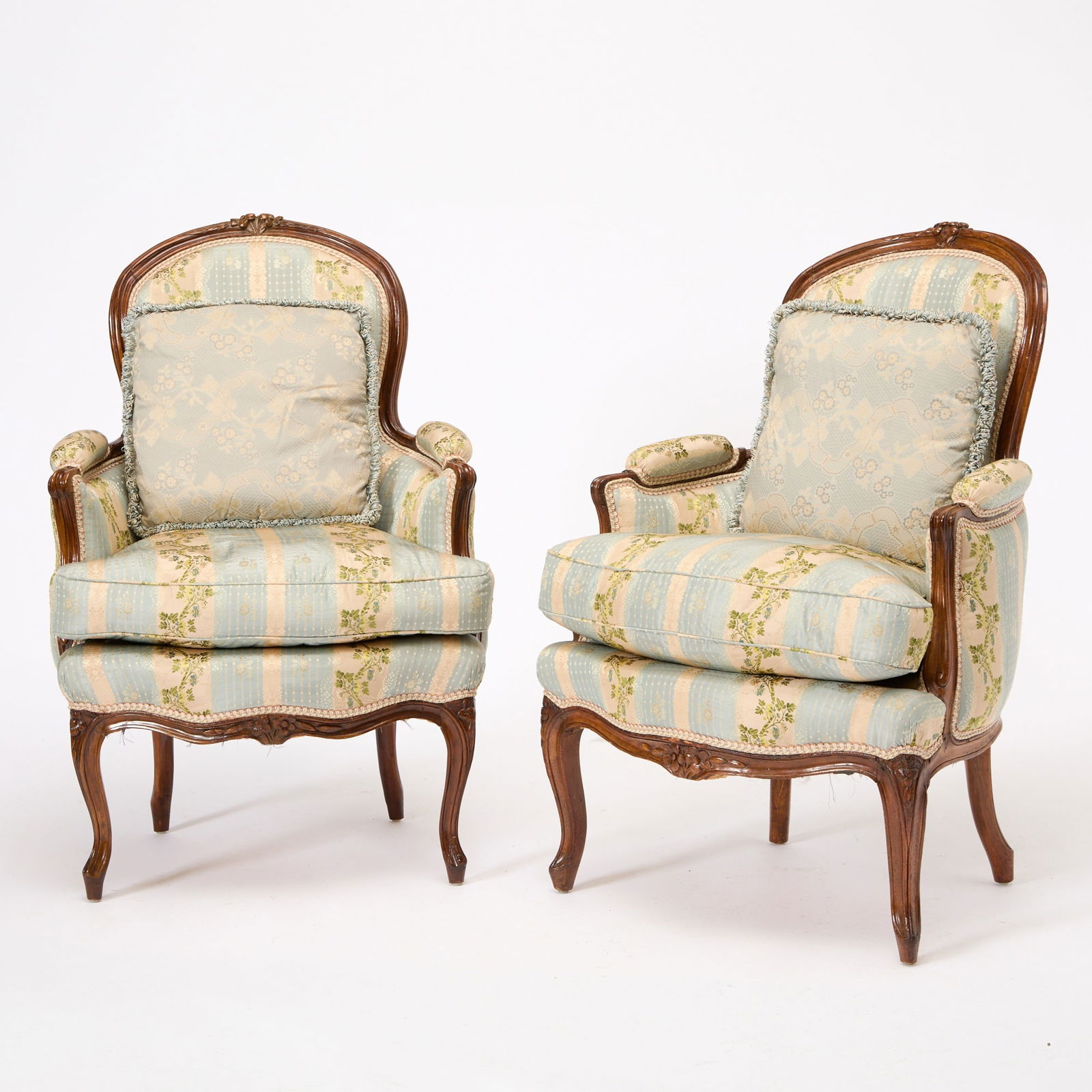 Pair of Louis XV Beechwood Bergères en Cabriolet: One mid-18th century, the other 19th century The padded back, arms, and squab cushion within a channeled frame, the toprail and seat-rail centered by flowerheads, on cabriole legs, covered in Lisere r