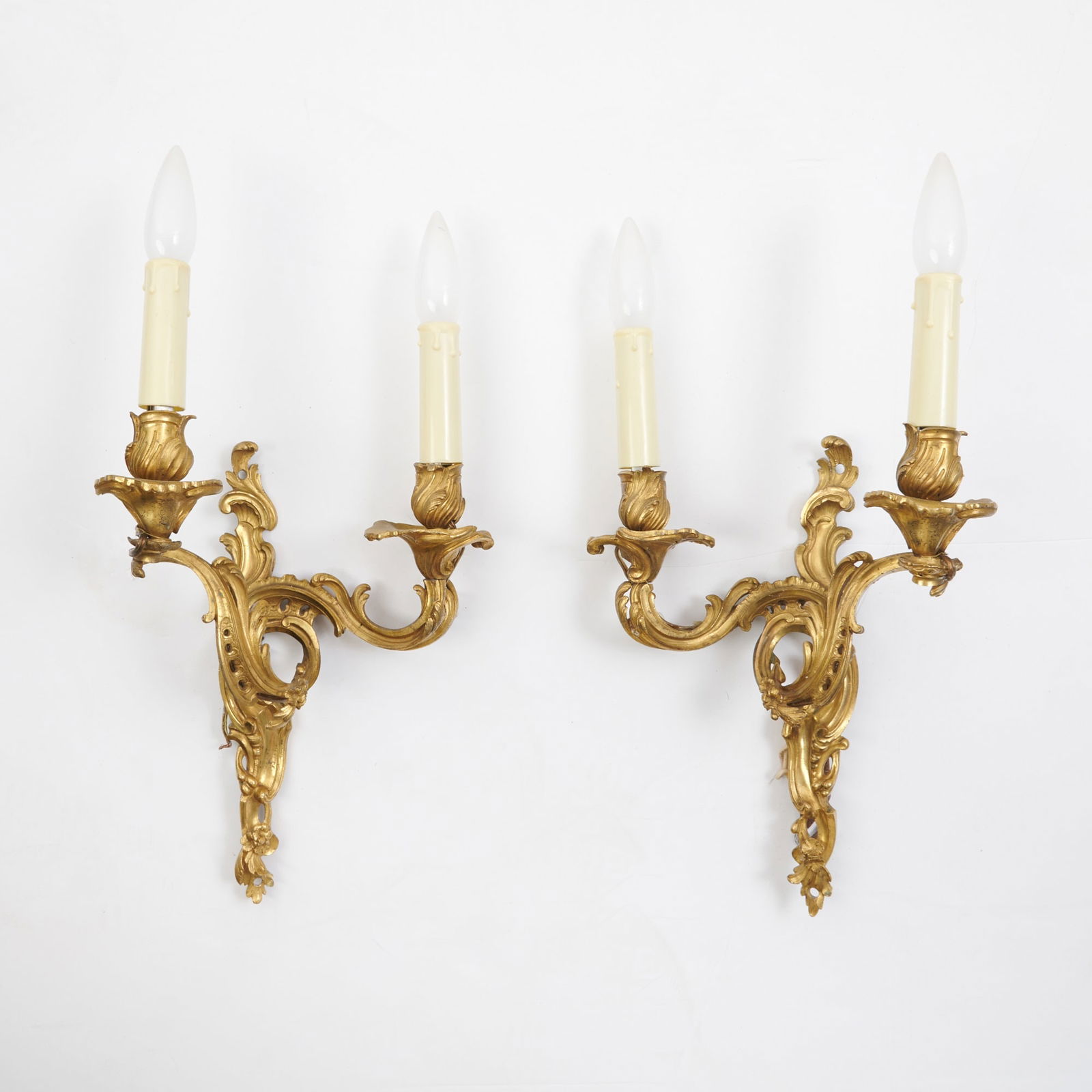 Pair of Louis XV Ormolu Two- Branch Wall-Lights: Mid-18th century Each with a pierced C-scroll and foliate backplate issuing conforming nozzles terminating in foliate drip-pans and nozzles, drilled for electricity. Height 12 inches (30.5 cm). Drill