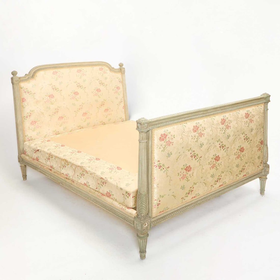 Louis XVI Grey-Painted Bed: Late 18th century, the side rails and central supports later The padded back and footboard within an arched lappeted and stiff-leaf carved frame, with fruiting finials on stop-fluted supports and flut