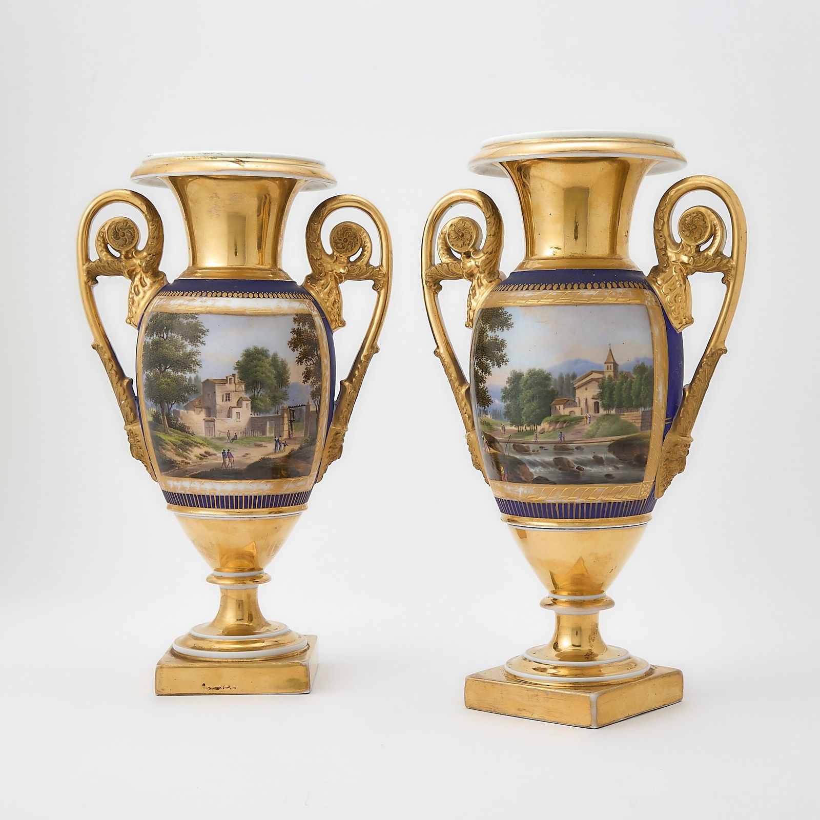 Pair of Paris Porcelain Gilt and Matte Blue Vases: Circa 1820-30 Each of ovoid form, the rise reserved with a landscape panel depicting rural scenes, one with figures on a path near a gate, the other with figures on a path down from a Church near a ri