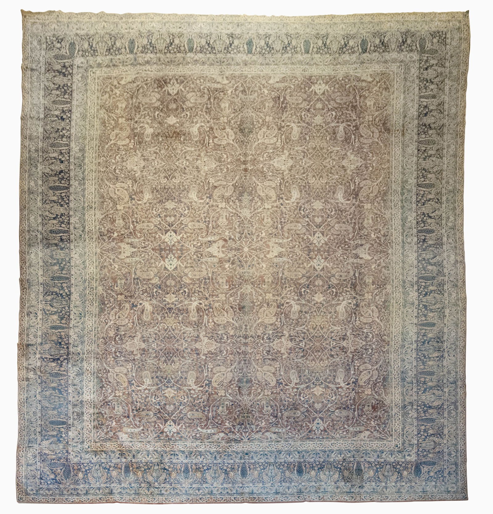 Kerman Carpet: Southeast Persia, First 1/4 20th Century The overall pattern of polychrome floral vinery on the caramel field is within an indigo spruce tree and boteh border. 19 feet 9 inches x 14 feet 4 inches. 