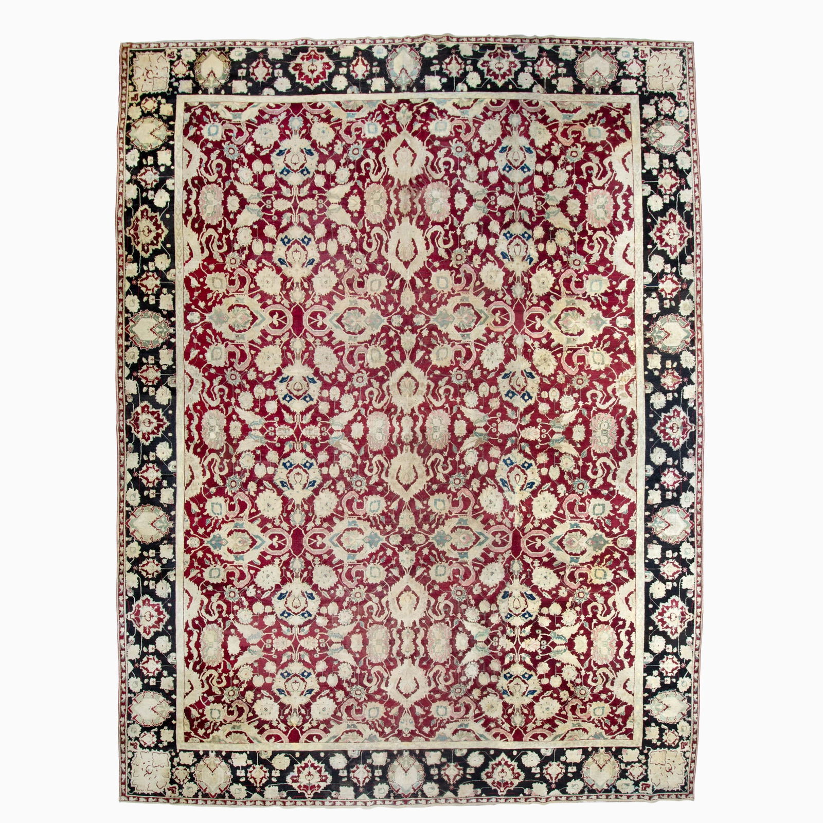 Agra Carpet: North India, Last 1/4 19th Century The 16th-century Isfahan design has an overall pattern of large palmettes amongst cloud bands on a crimson field within a charcoal border. 17 feet 7 inches x 13