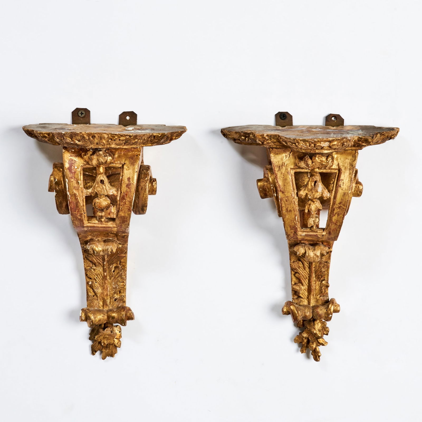Pair of Régence Carved Giltwood Brackets: Circa 1720 Each with shaped rectangular shelf carved with foliate edging, supported by an openwork scrolling console carved with acanthus leaves, C-scrolls and rocailles, the lower section terminating