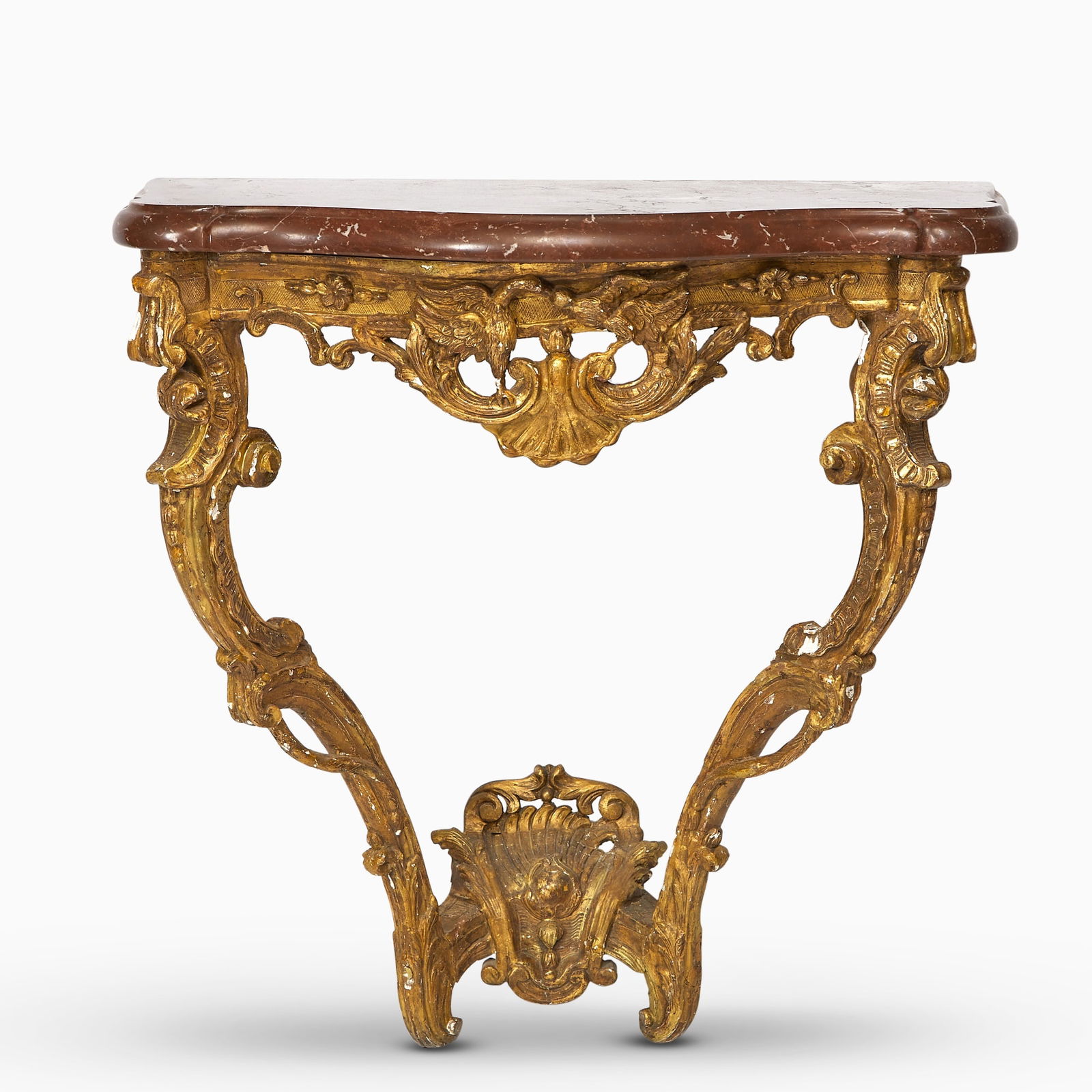 Louis XV Carved Giltwood Console Table: Circa 1750 The serpentine red marble top above a deeply carved apron centred by a scallop shell and scrolling rocailles, supported on scrolled cabriole legs carved with acanthus leaves and rocailles,