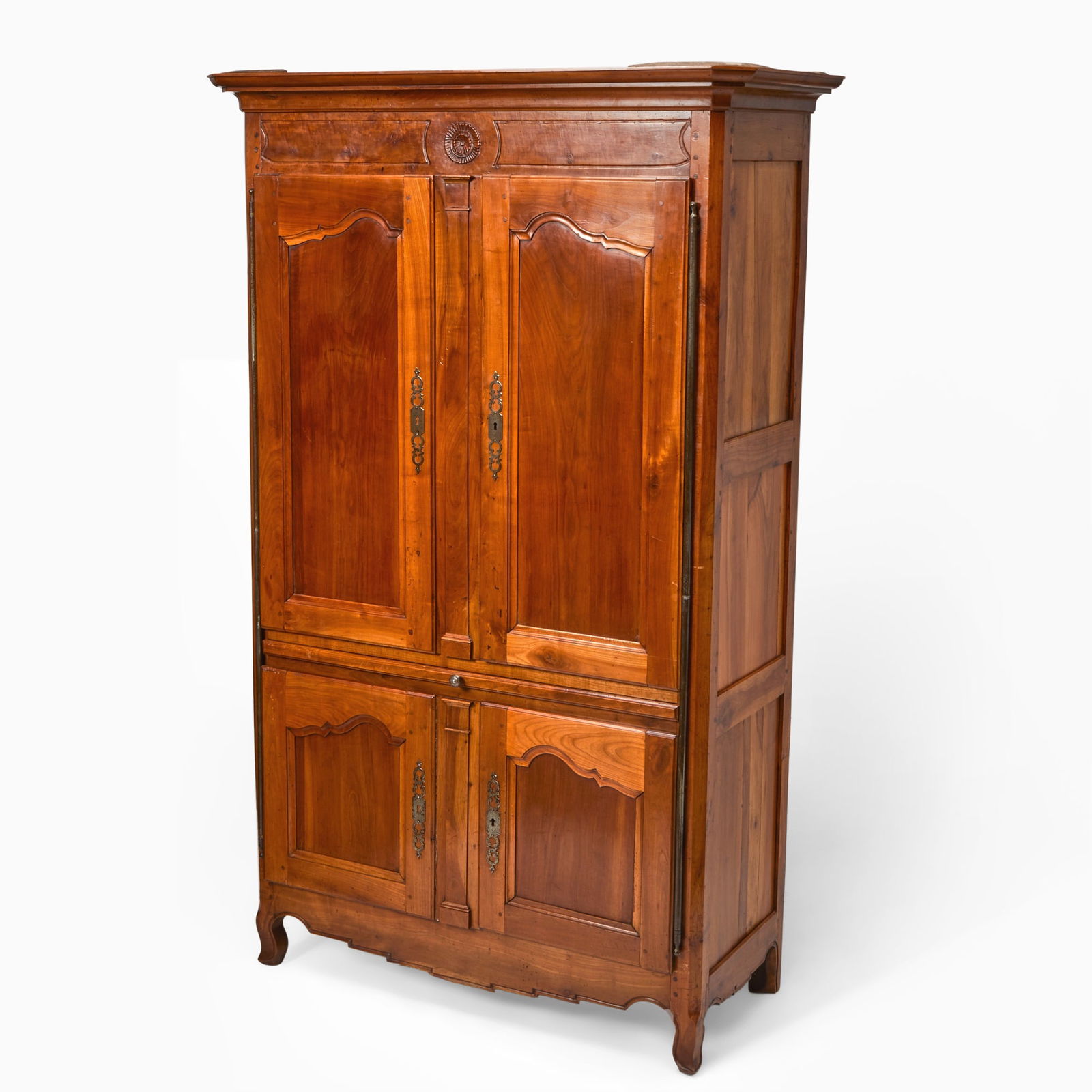 Louis XV Provincial Cherry and Fruitwood Cabinet: Mid 18th century The molded top over a carved frieze centered by a rosette over two panel doors enclosing a later fitted interior with shelves and a slide, further over two cupboard doors enclosing a