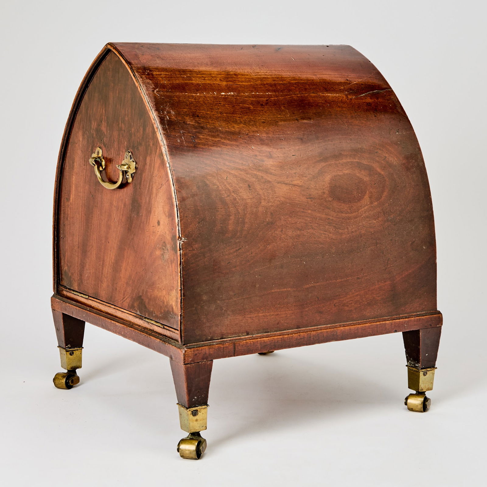 George III Mahogany Wine Cellarette: Late 18th century Of lancet form with brass pulls, the hinged door enclosing a fitted green-baize lined interior, on tapering square legs, brass caps and casters, bearing paper label 'From the H.C. FO