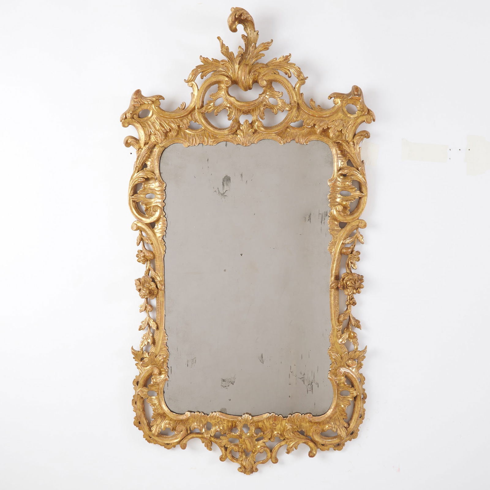 George II Giltwood Mirror: Circa 1760The later rectangular mirror plate within a C-scroll and foliate pierced border, surmounted by a foliate clasp.Height 52 inches (132 cm), width 28 inches (71.1 cm). With previous