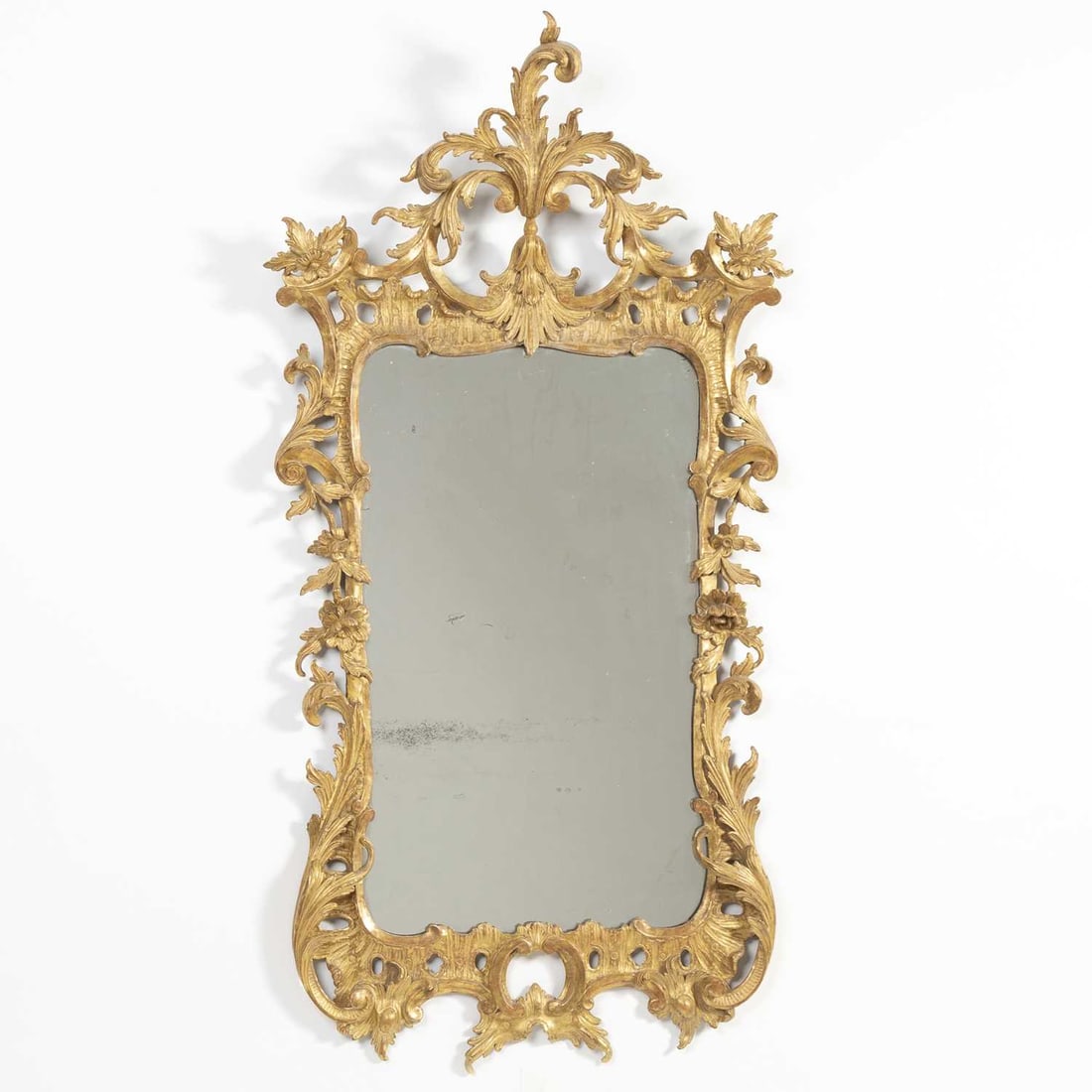 George II Giltwood Mirror: Circa 1755The rectangular mirror plate within a pierced ruffle and foliate-scrolled surround, the foliate and acanthus-scroll cresting above confronting C-scrolls.Height 55 inches (139.7 cm), width