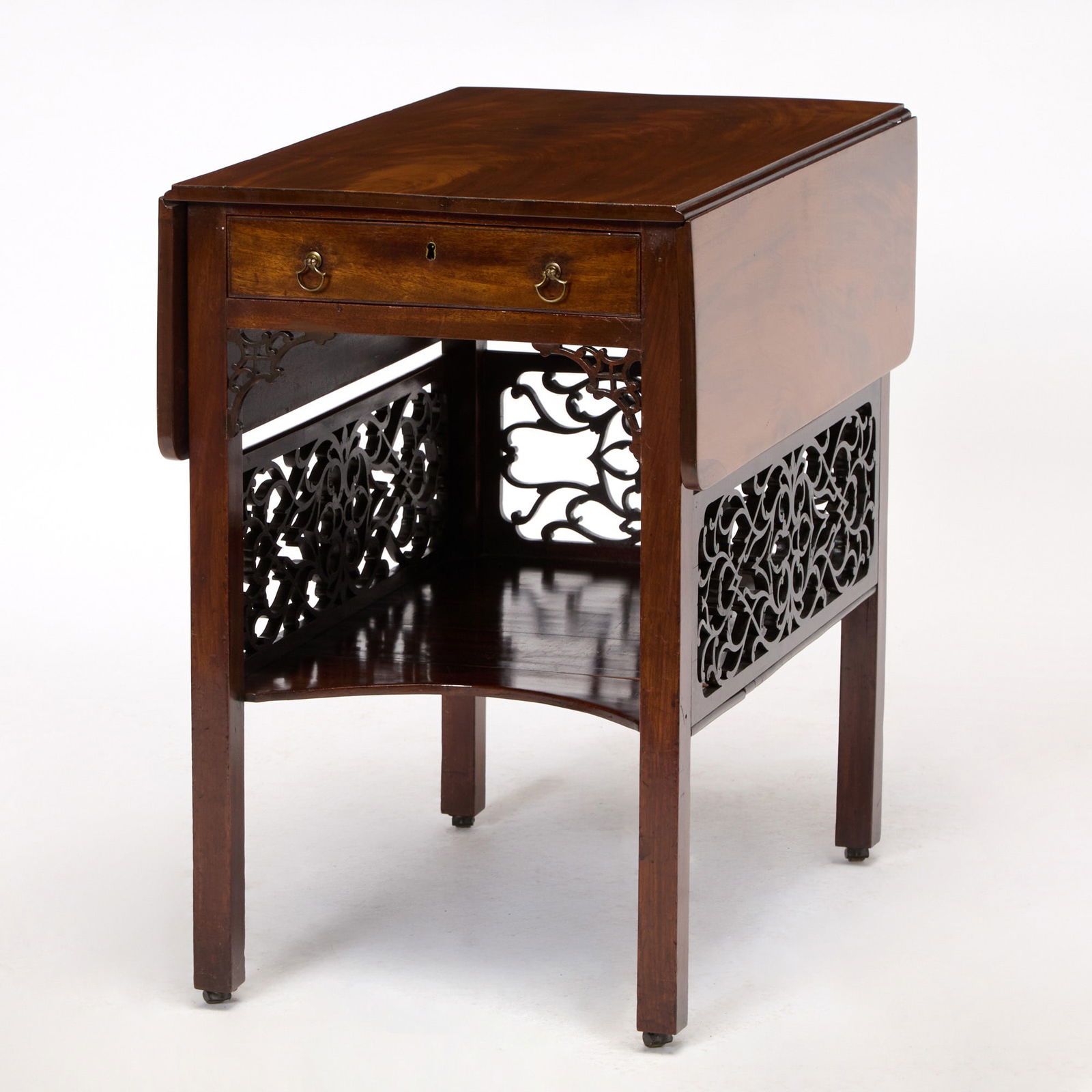 George III Mahogany Pembroke Table: Third quarter 18th centuryThe rectangular top and rounded flaps above a frieze drawer on chamfer legs joined by a plinth, enclosed by pierced arabesque, on castors; the underside and interior drawer