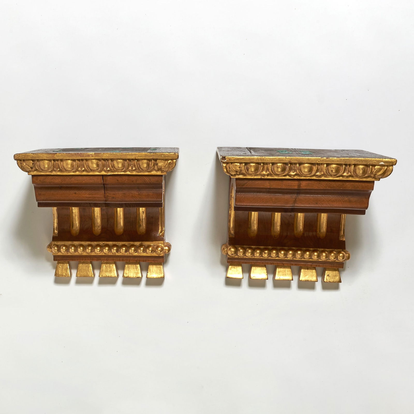 Pair of George II Style Mahogany and Parcel-Gilt Wall Brackets: Late 19th/20th century Each with an egg-and-dart border over a concave fluted beaded support with dentil pendants. Height 12 1/4 inches (31.1 cm), width 13 inches (33 cm), depth 12 1/2 inches (31.7 cm