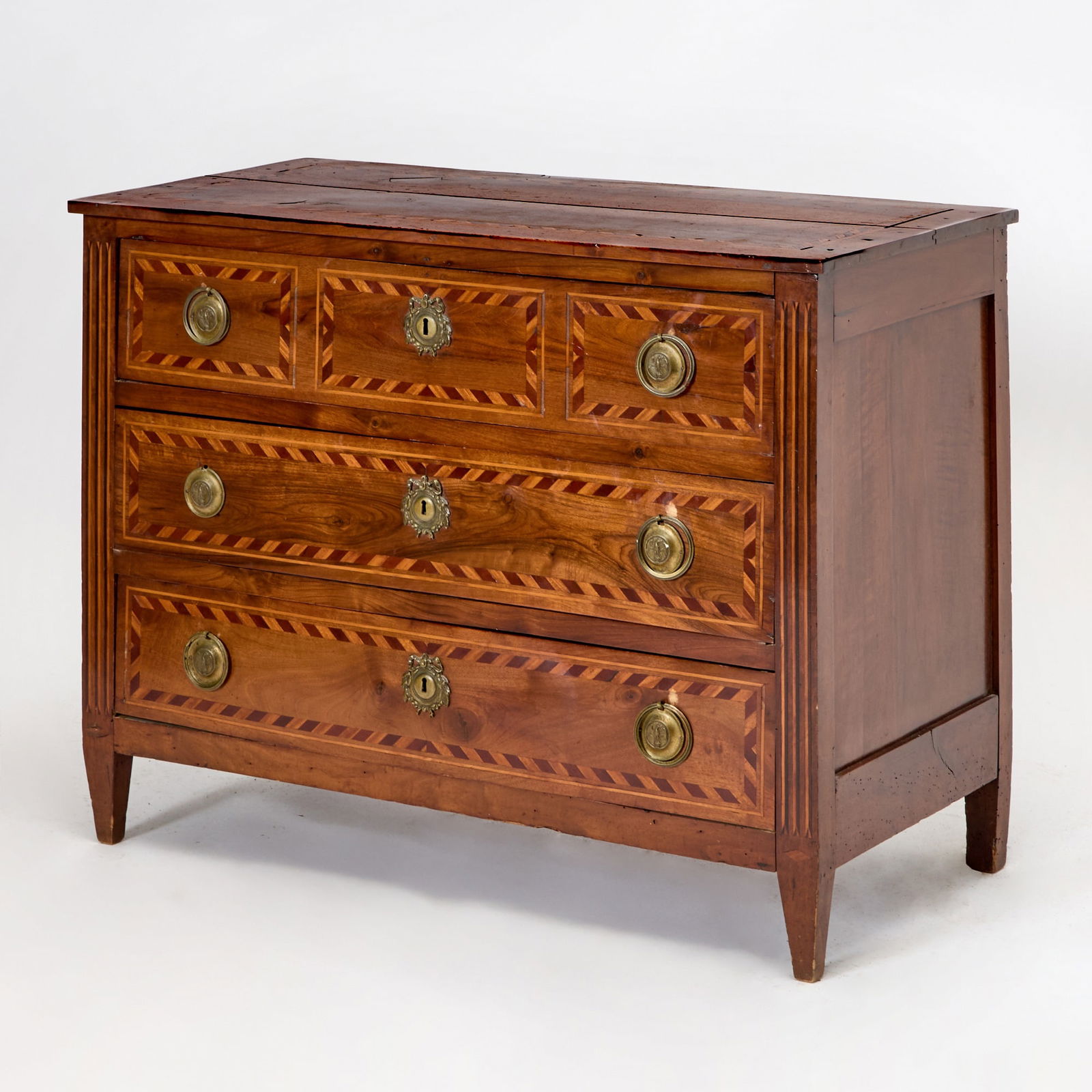 Italian Neoclassical Inlaid Walnut Commode: Probably Piedmont, late 18th century Cross-banded in mahogany, the paneled rectangular top over three long drawers, on tapering square legs. Height 33 1/4 inches (84.4 cm), width 44 inches (111.7 cm).