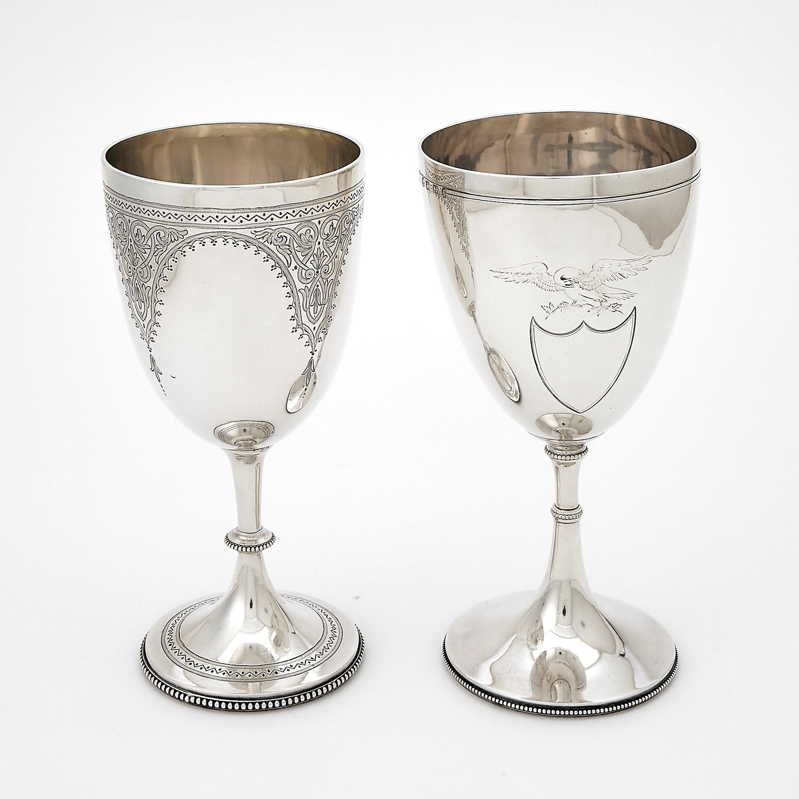 Two Victorian Sterling Silver Goblets: The larger engraved with shield surmounted by an eagle, marked J.B. Carrington, Birmingham, 1877, height 8 inches (20 cm); the smaller engraved with scrolling panels, marked Henry Holland, London,