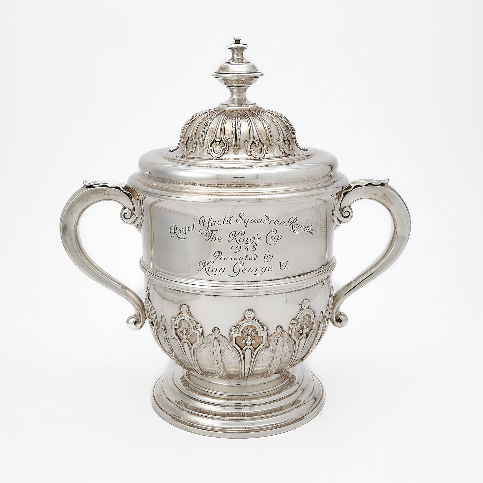 Yachting Interest: George VI Sterling Silver Two Handled Covered Cup: Heming & Co., London, 1937 The base and cover with applied strapwork , the body engraved Royal Yacht Squadron Regatta The King's Cup 1938 Presented by King George VI. Height overall 14 1/2 inches