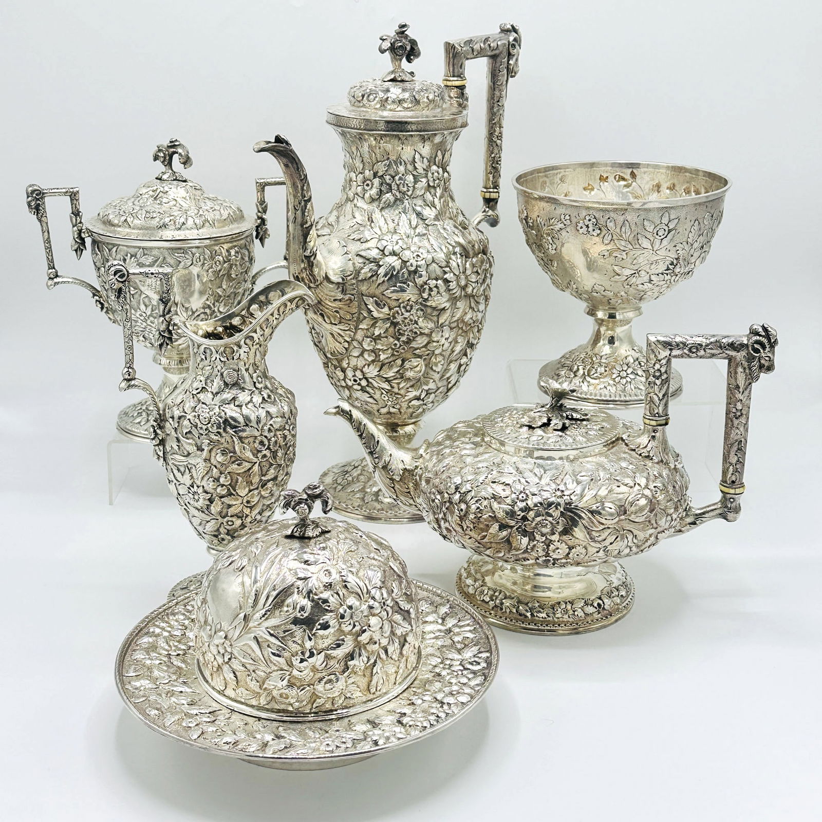 Assembled American Silver Repousse Tea and Coffee Service: S. Kirk & Son, Baltimore, late 19th/early 20th century Chased overall with foliate scrolls, the angular loop handles with rams head, comprising a coffee pot, teapot, covered sugar bowl, cream jug,