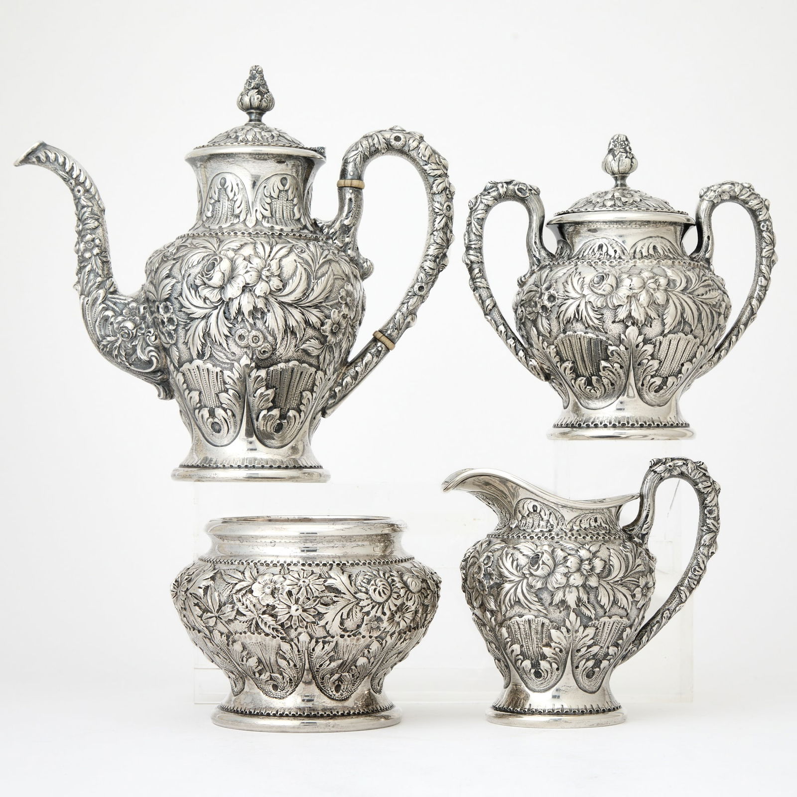 American Sterling Silver Tea and Coffee Service: S. Kirk & Son Inc., Baltimore, 1926-1932 Each chased overall with flowers and foliage, comprising a teapot, cream jug, covered sugar bowl, and waste bowl. Height of teapot 9 1/2 inches, total approxim