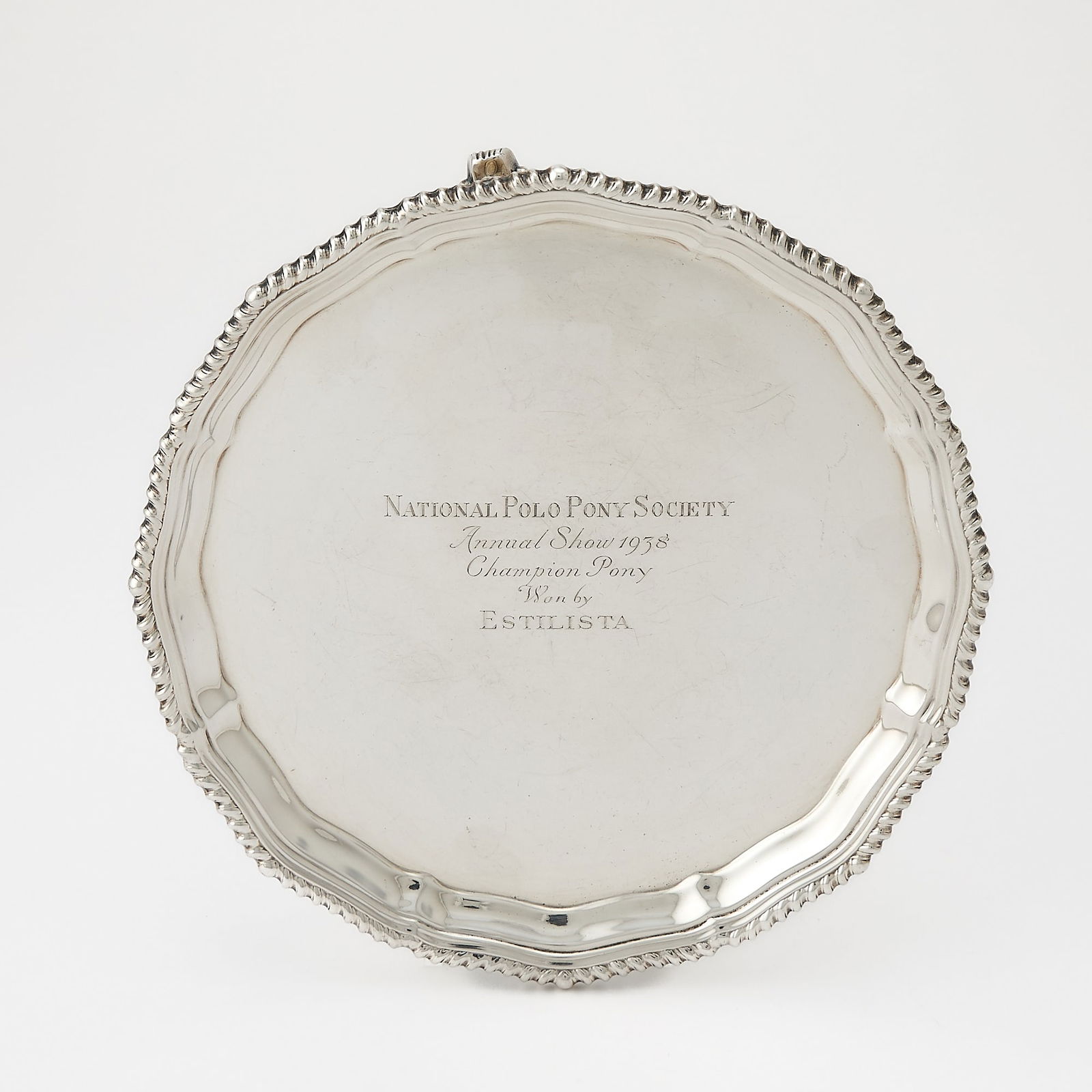 George VI Sterling Silver Polo Trophy Salver: Peter Guille, London, 1938 Circular, on three scroll feet, with gadrooned border, engraved National Polo Pony Society Annual Show 1938, Champion Pony Won by Estilista, marked on reverse. Diameter 8 1/