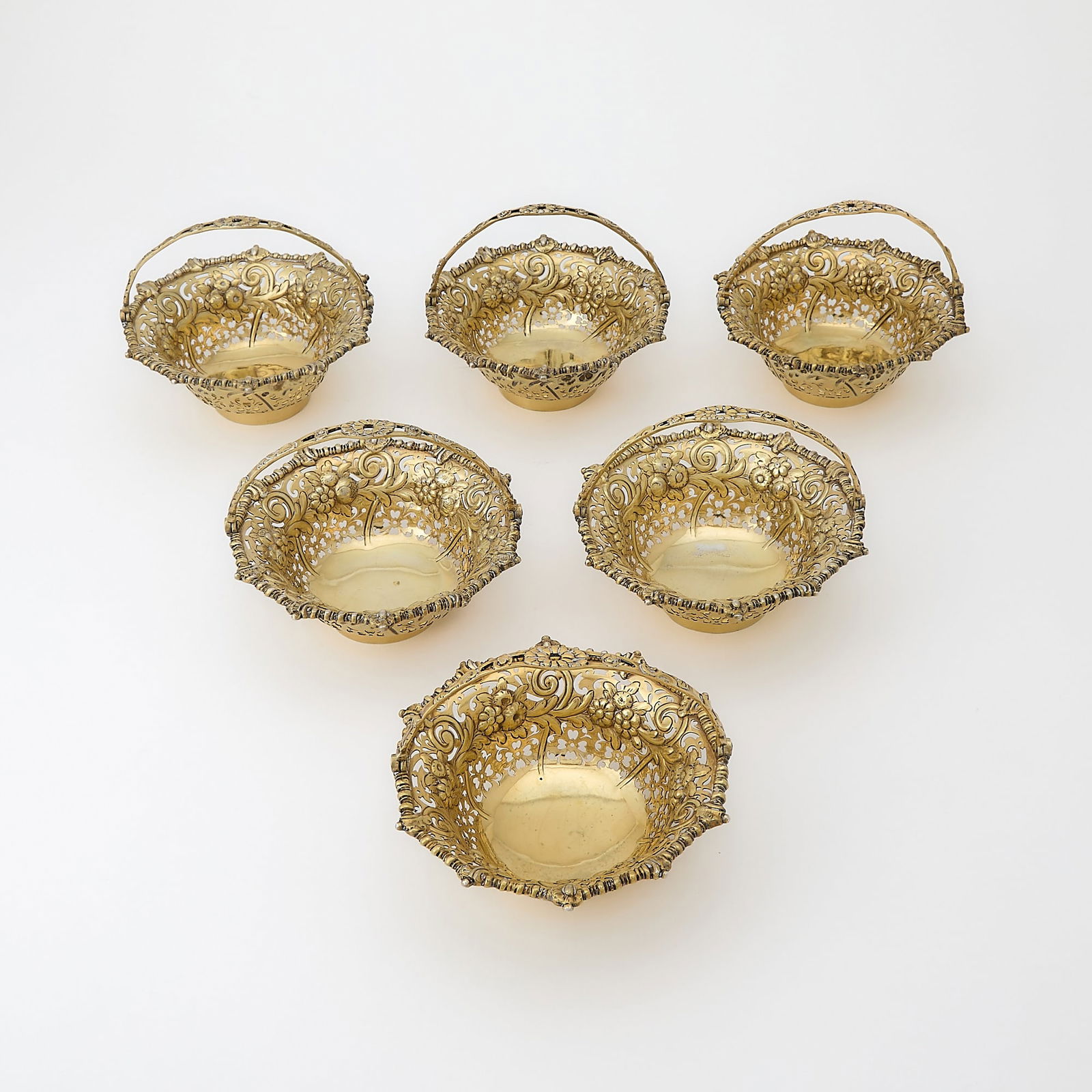 Set of Six George III Sterling Silver-Gilt Baskets: London, circa 1765 Each in the form of hanging epergne baskets, pierced and chased with flowers, part marked on bases and handles. Diameter of baskets 5 inches; total approximately 40 ounces. Qty: (6)