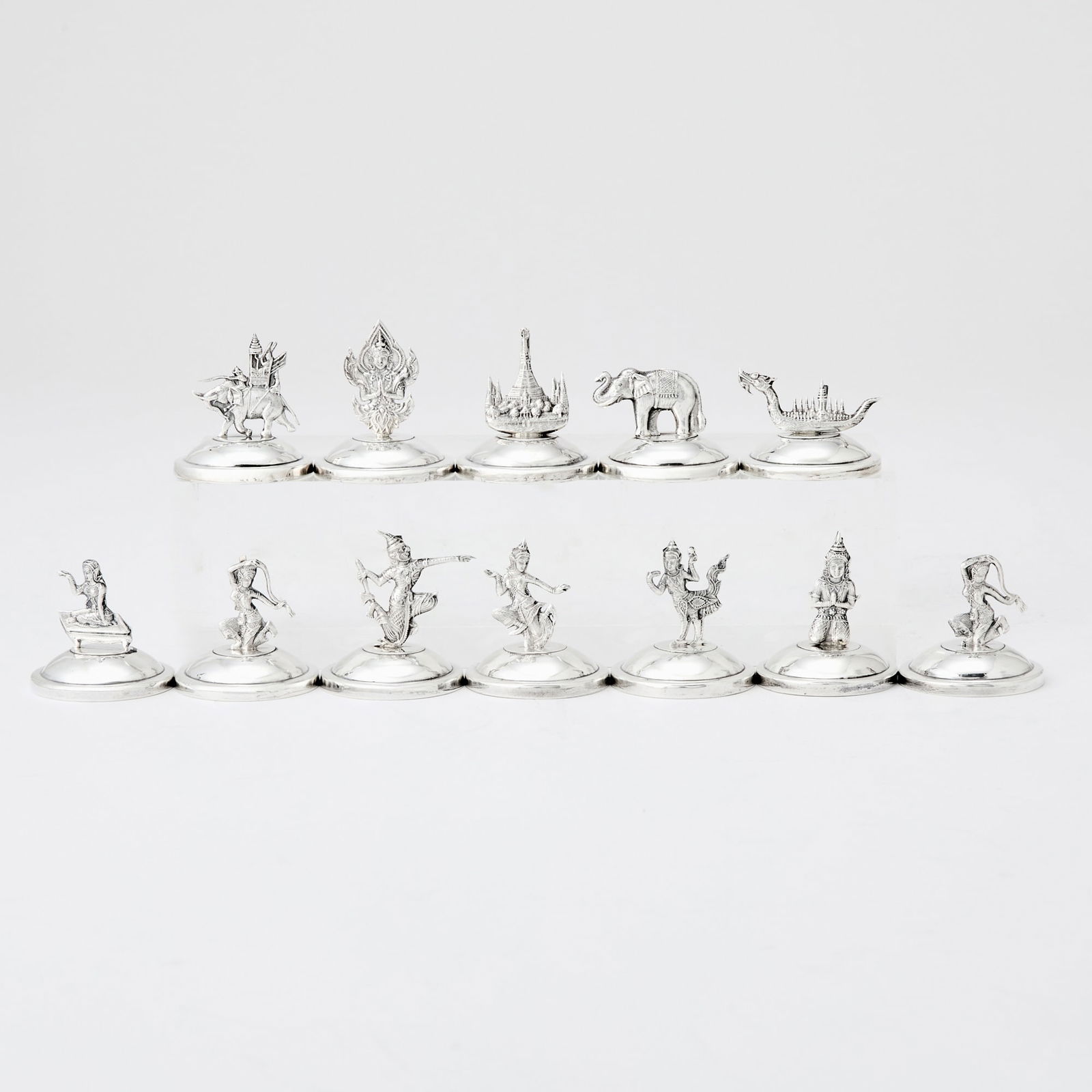 Set of Twelve Thai Sterling Silver Place Card Holders: 20th Century Designed with various motifs, including elephant, dragon boat, each on circular base, weighted, marked Siam Sterling. Diameter 1 1/2 inches. Another set of 12 place