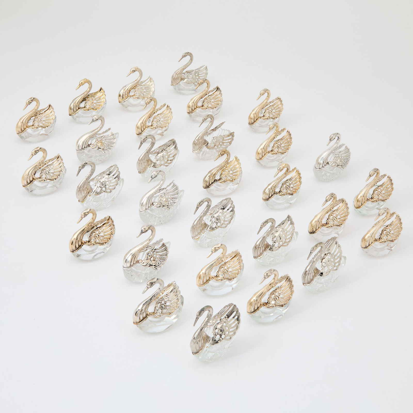 Group of Thirty Silver Plated and Glass Swan-Form Salt Cellars: The swans with movable wings, oval glass bowls, apparently unmarked. Length 3 inches. Three of the swans need regluing to glass bowls, and others are reguled. Some of the wings are loose. There are f