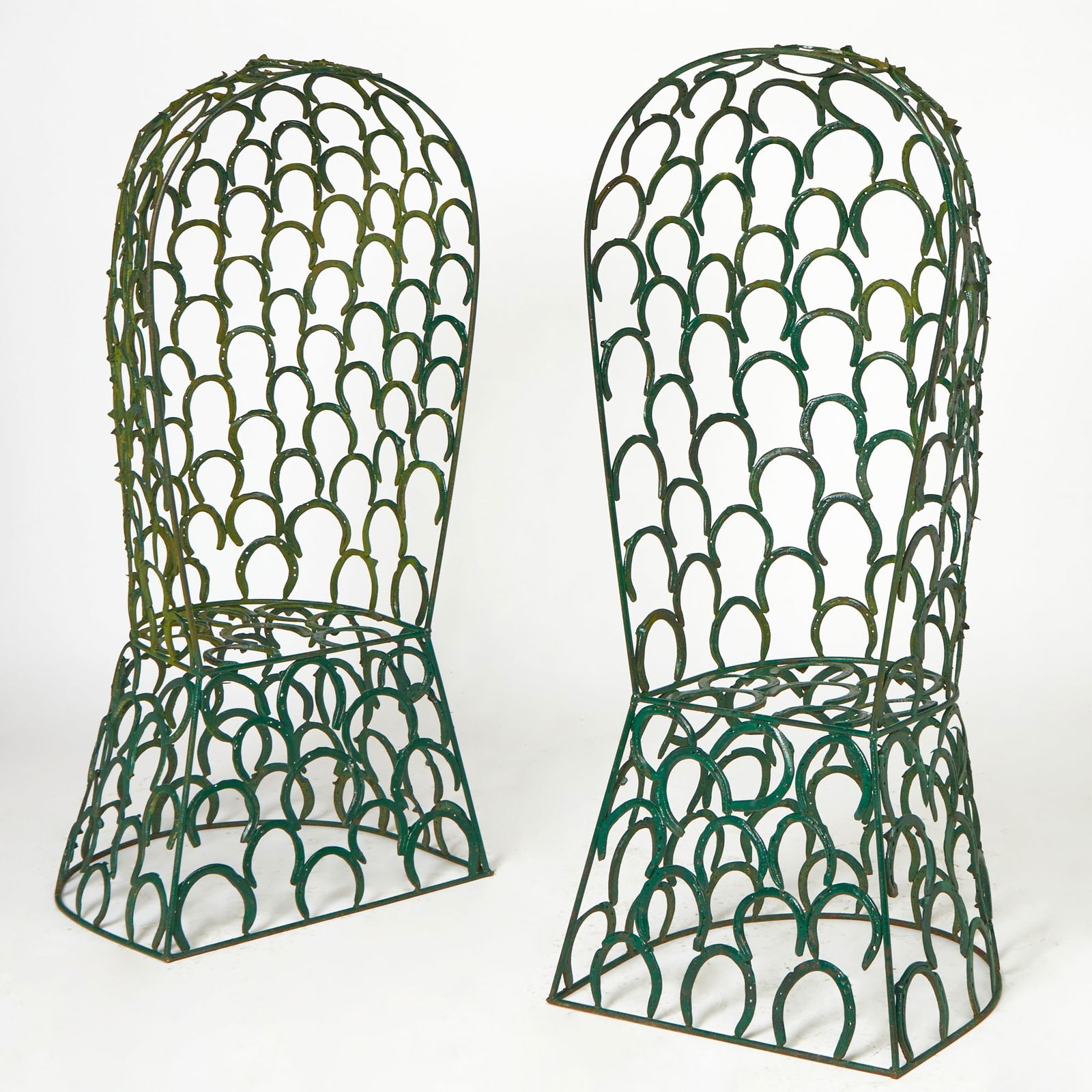 Pair of Green Painted Metal Horseshoe Garden Chairs: Made with several horseshoes welded together. Height 64 inches, width 25 1/2 inches, depth 17 1/2 inches.