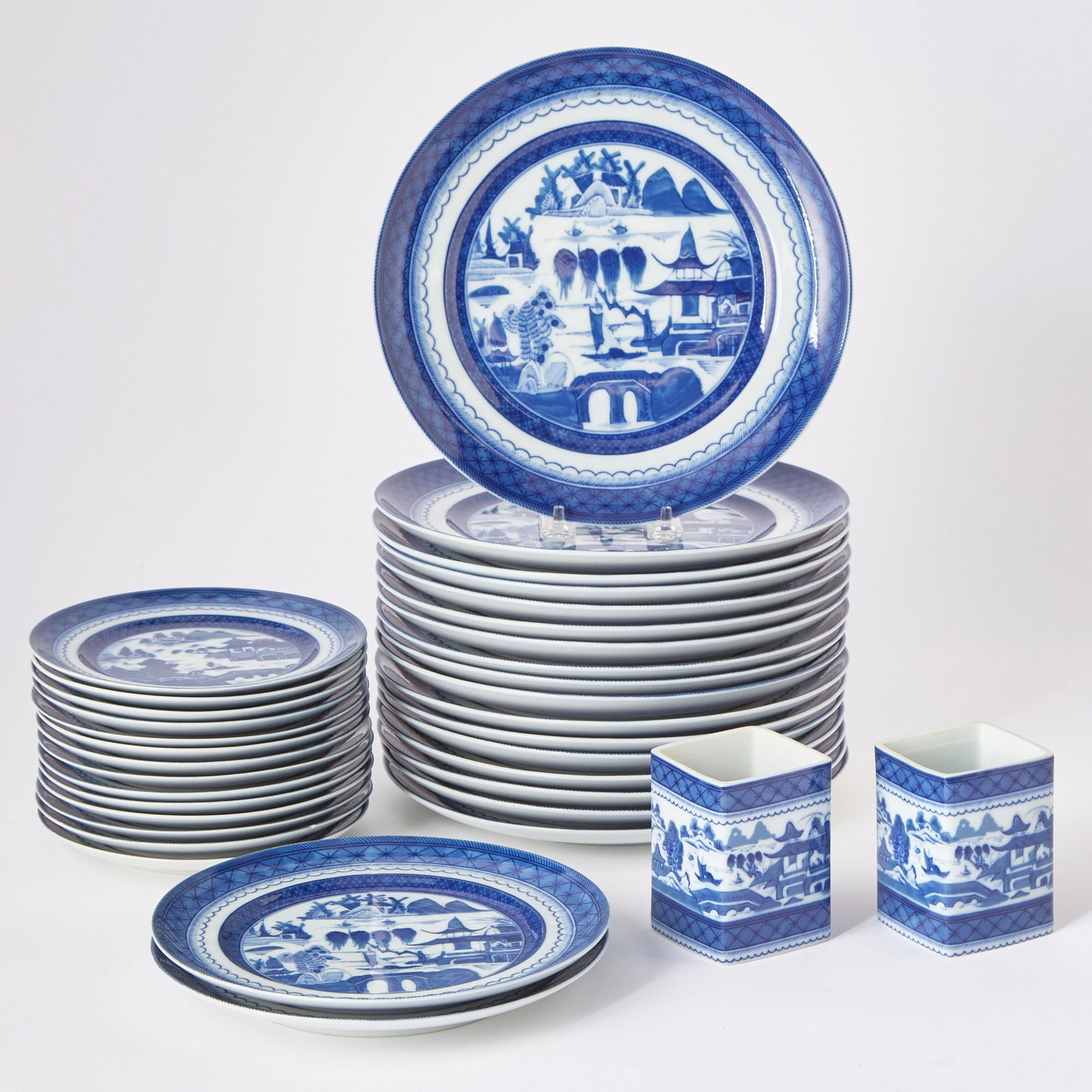 Group of Mottahedeh Blue and White Canton Pattern Plates and Holders: Historic Charleston Reproductions, made in Portugal.Comprising:Seventeen dinner plates, diameter 10 inchesFourteen salad/dessert platesTwo small square holders(33)